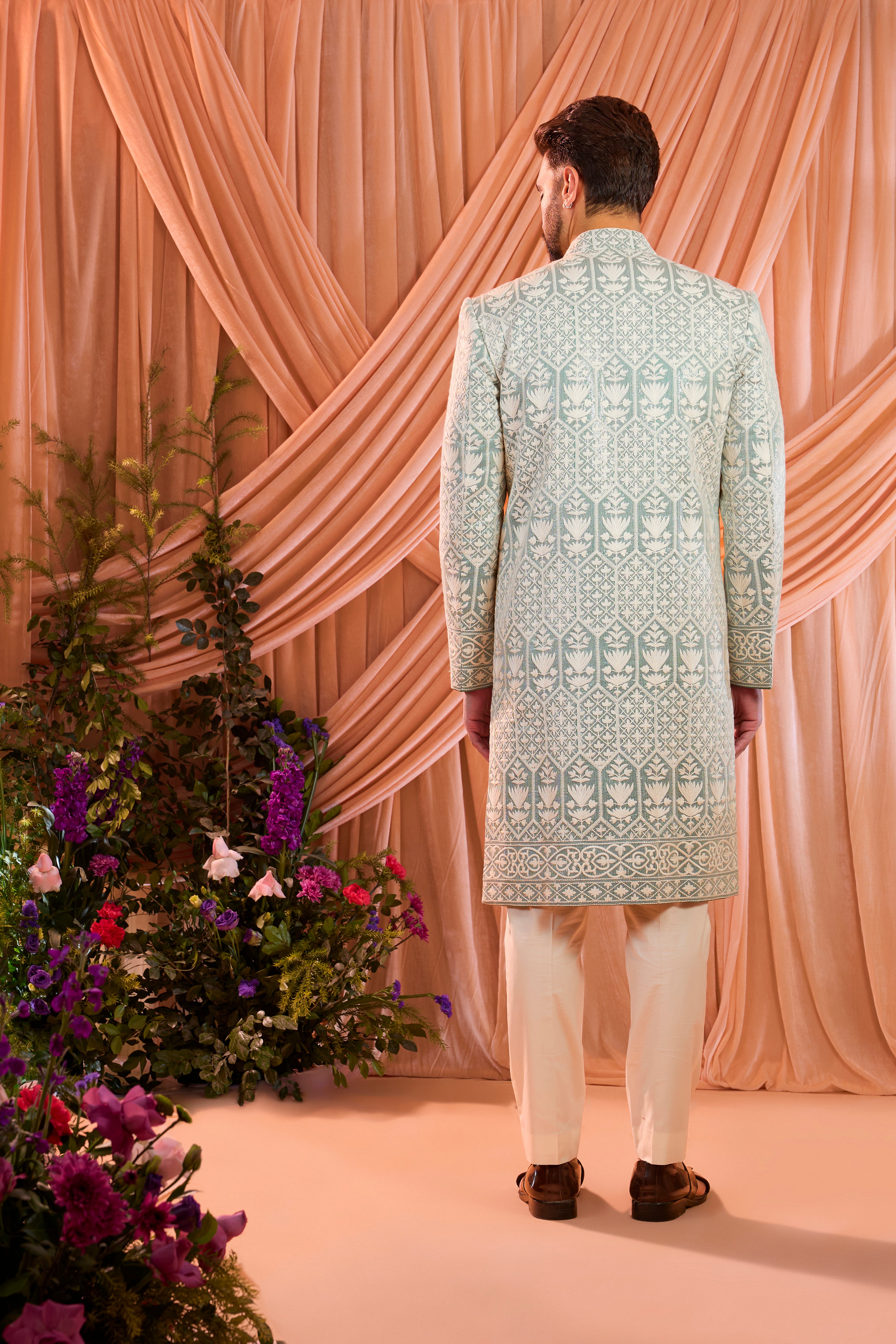 An aqua blue chikankari sherwani distinguished by heavy ivory threadwork and meticulously detailed sequin embellishment.