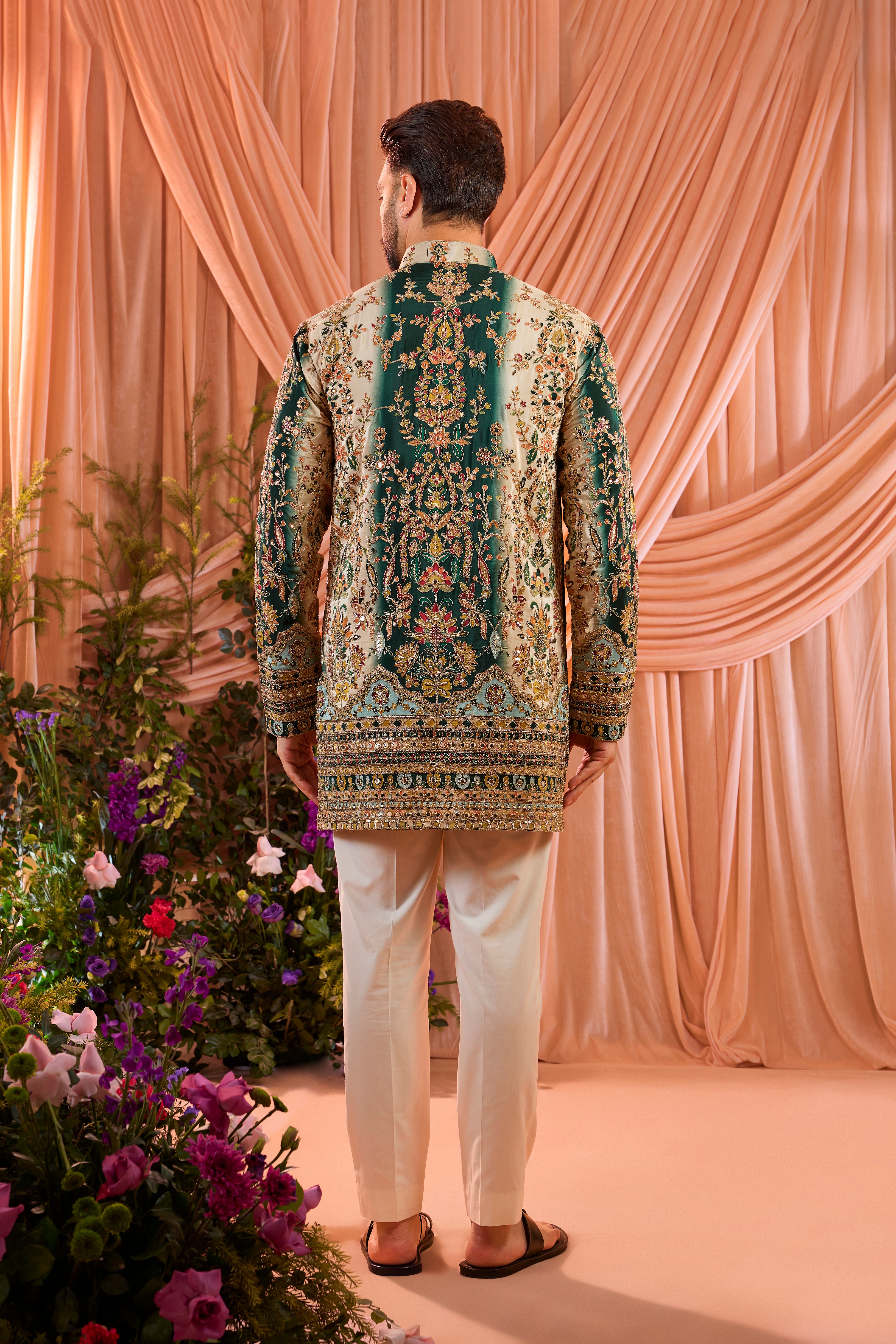 A green and gold short kurta adorned with detailed floral embroidery and shimmering sequin accents