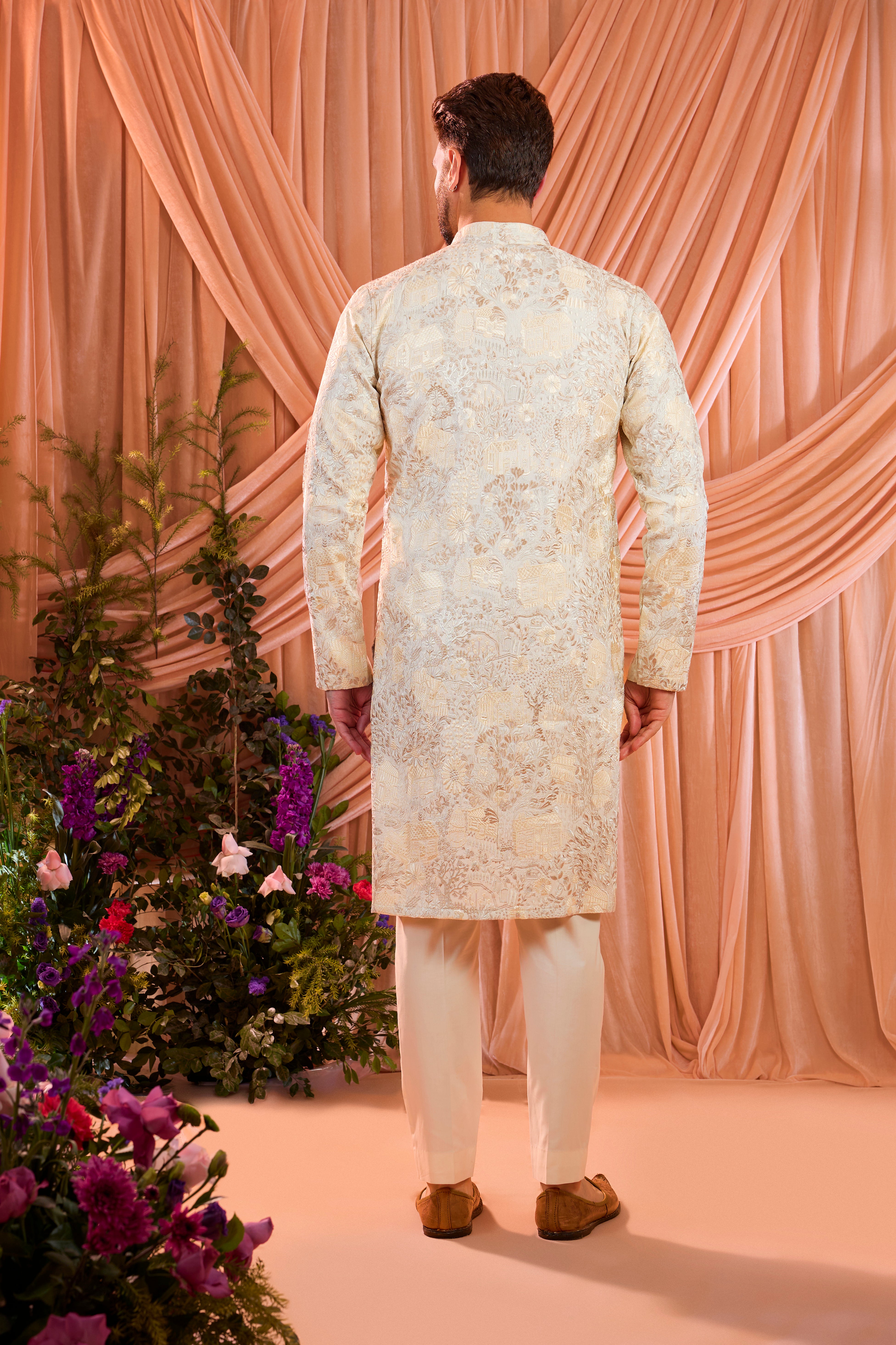 A cream tropical chikankari kurta enriched with intricate threadwork and detailed floral motifs, inspired by a vintage homes era.