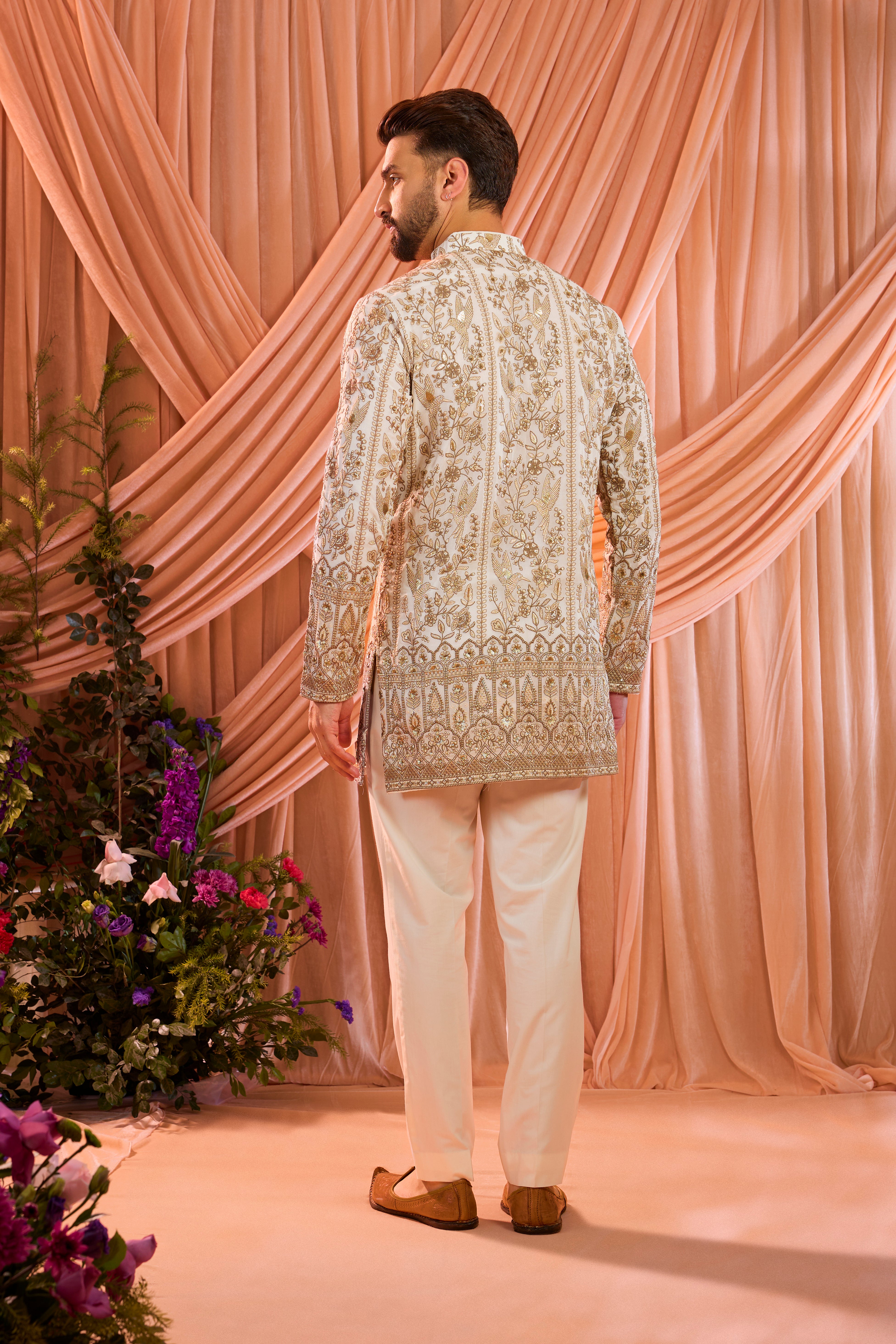 A white short chikankari kurta adorned with intricate flora and fauna motifs, reflecting refined artisanal craftsmanship.