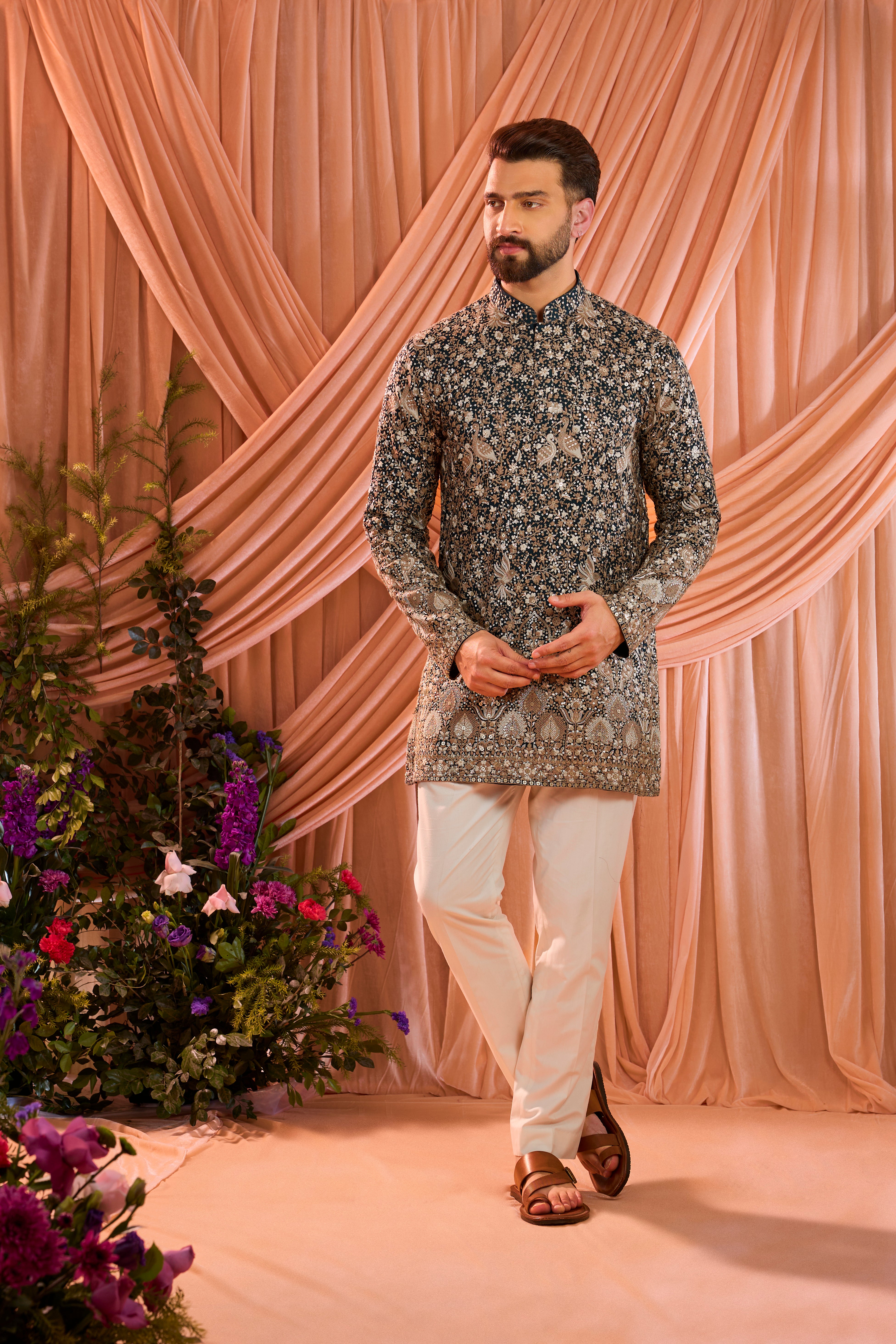A teal short kurta adorned with intricate sequin embellishment, brought to life by detailed flora and fauna figures.