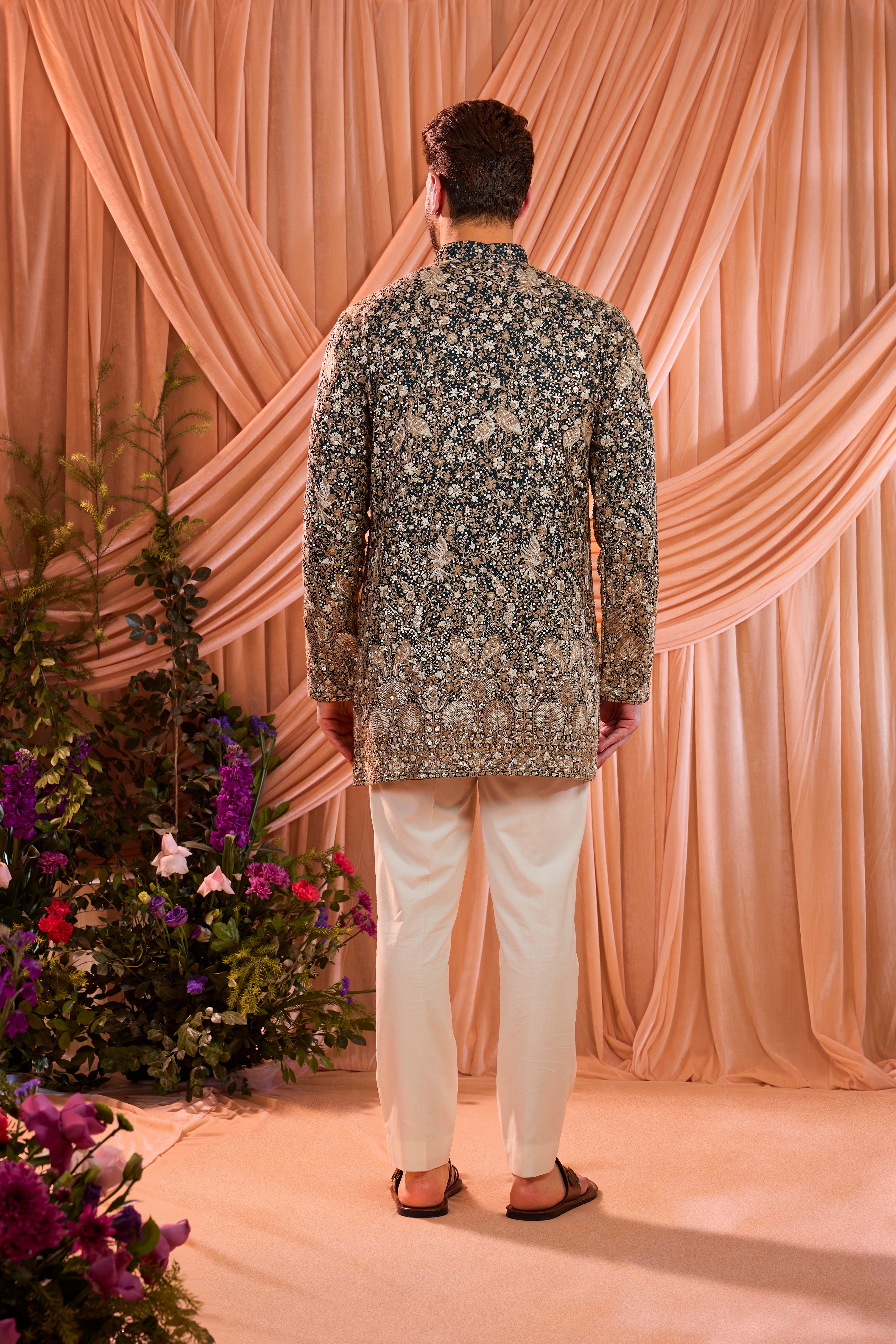 A teal short kurta adorned with intricate sequin embellishment, brought to life by detailed flora and fauna figures.