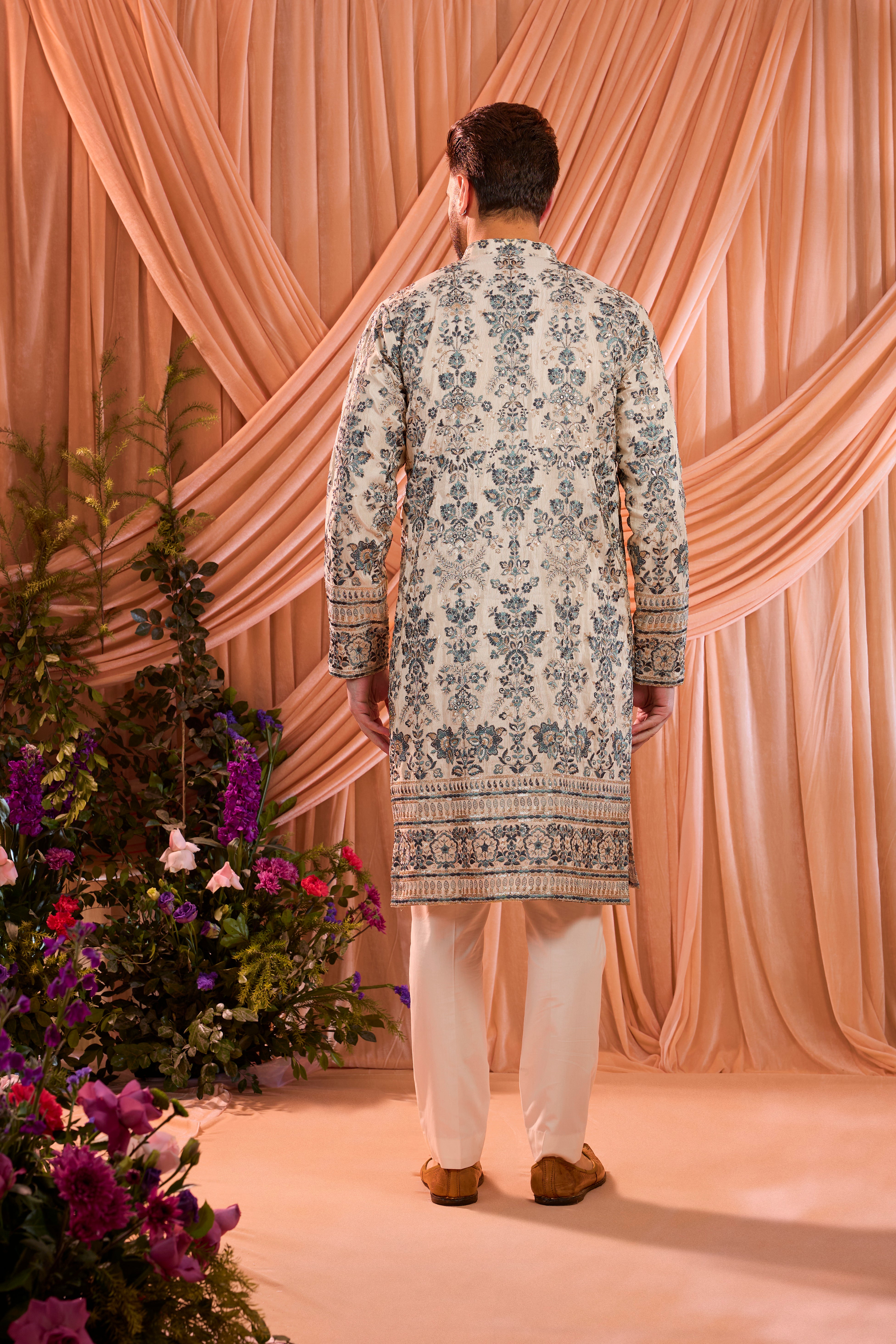 A light golden short floral chikankari kurta accented with delicate blue threadwork, enriched by zari and subtle sequin detailing.