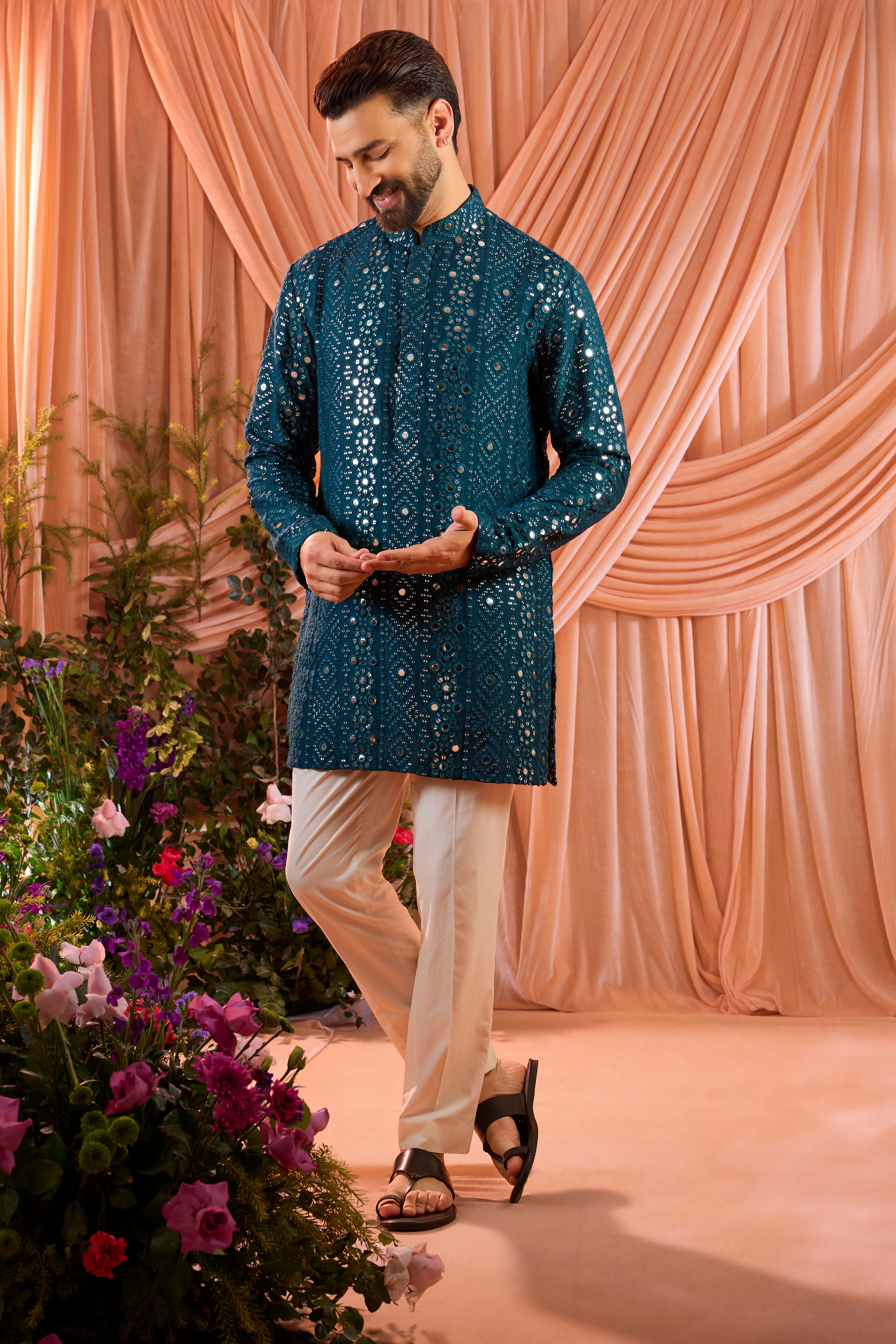 A signature teal short kurta featuring mirror-inspired sequin work that recreates the brilliance of traditional mirror craftsmanship. The refined surface detailing adds depth and controlled shimmer.