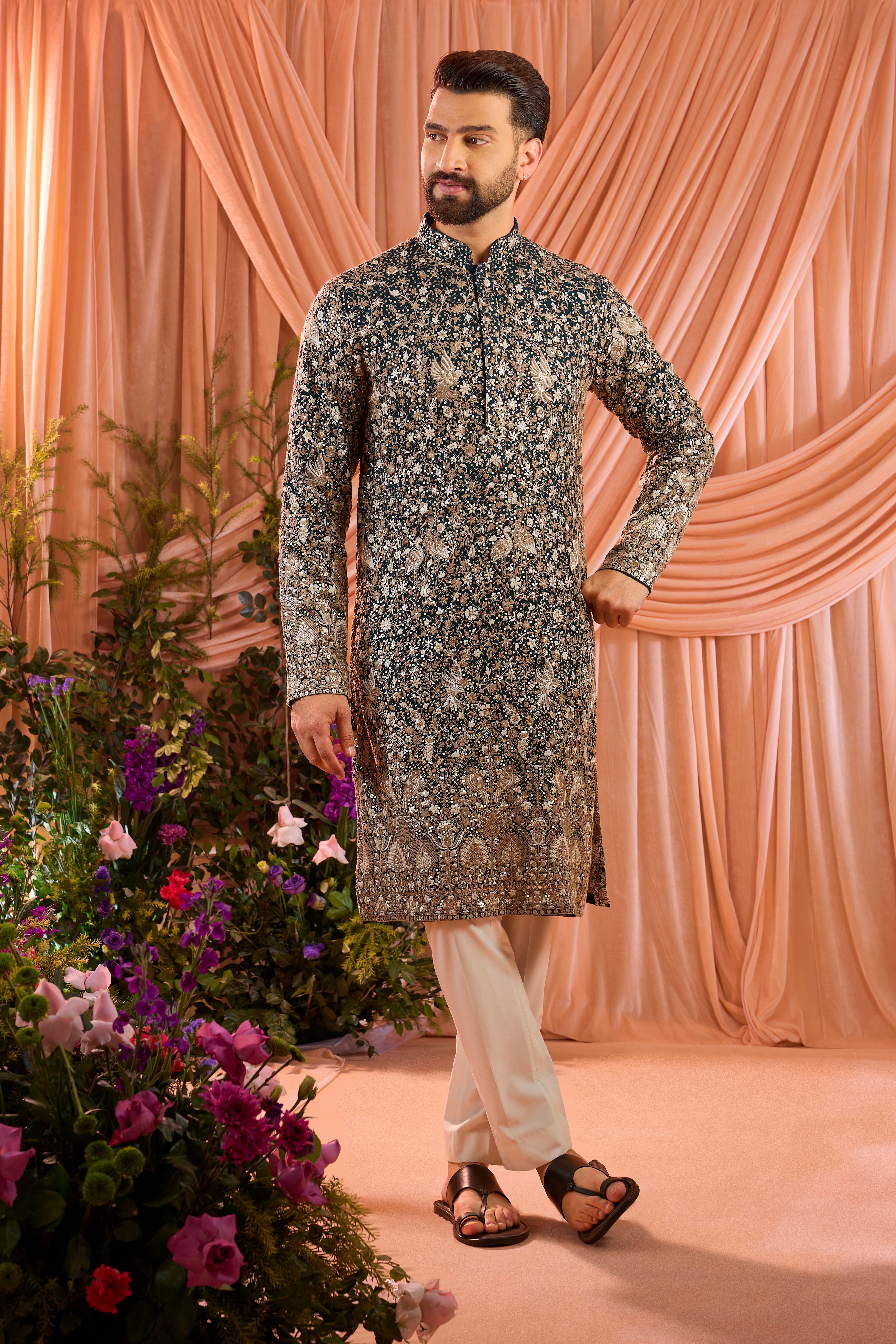 A teal long kurta adorned with intricate sequin embellishment, brought to life by detailed flora and fauna figures.