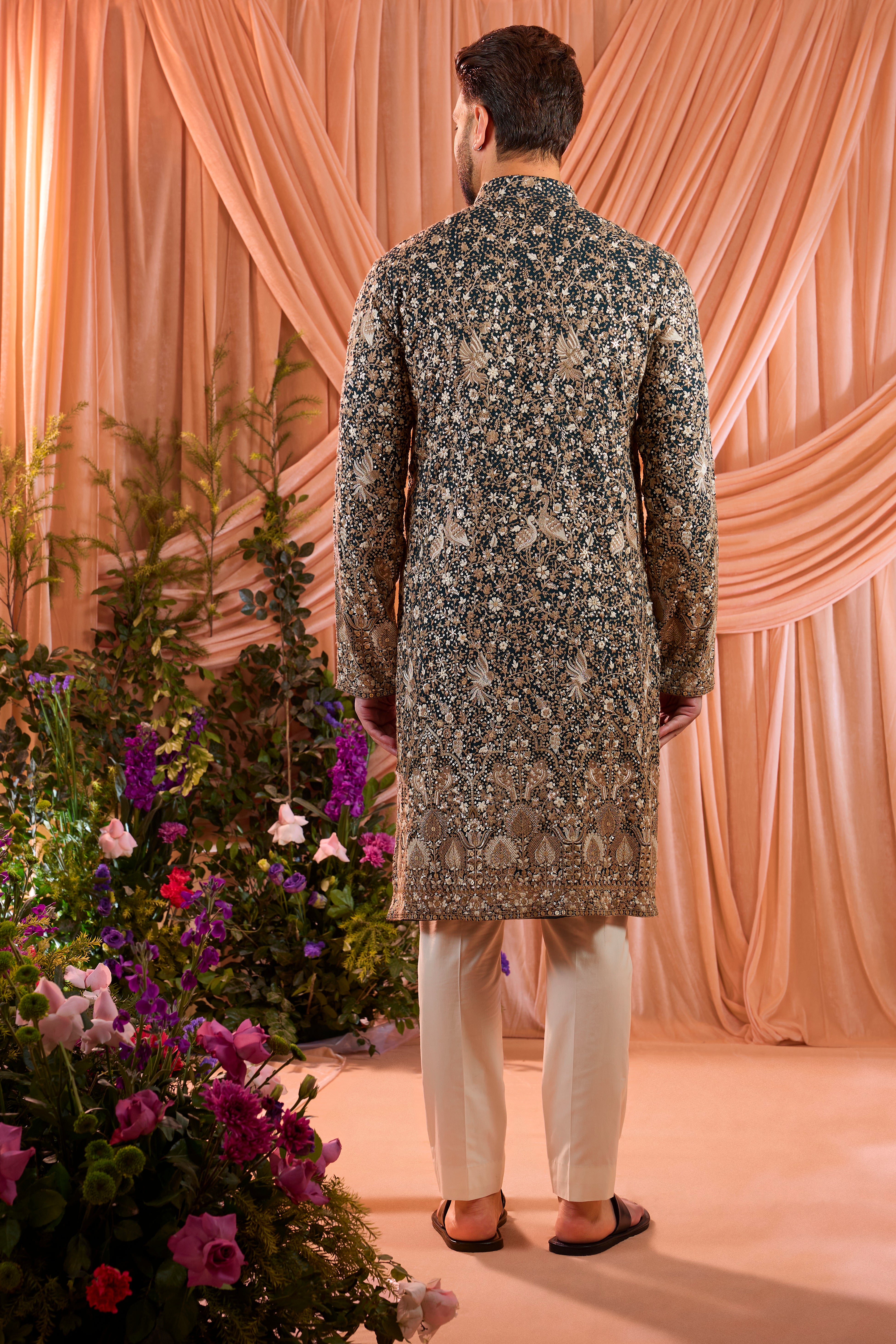 A teal long kurta adorned with intricate sequin embellishment, brought to life by detailed flora and fauna figures.
