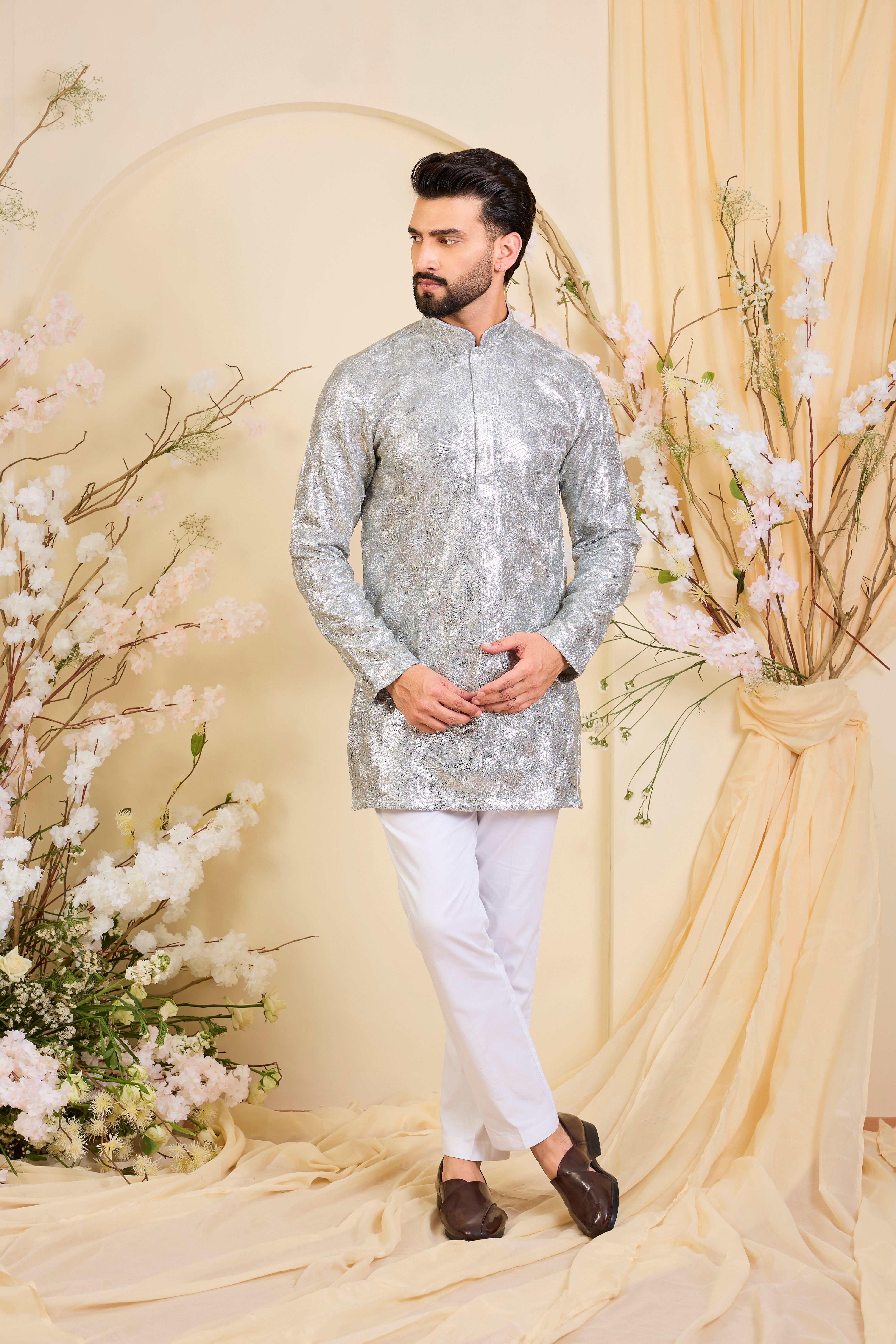 A luminous silver short kurta encrusted with dense, zari-like sequin work, delivering intense shine and intricate, high-impact detailing. Made to stand out.