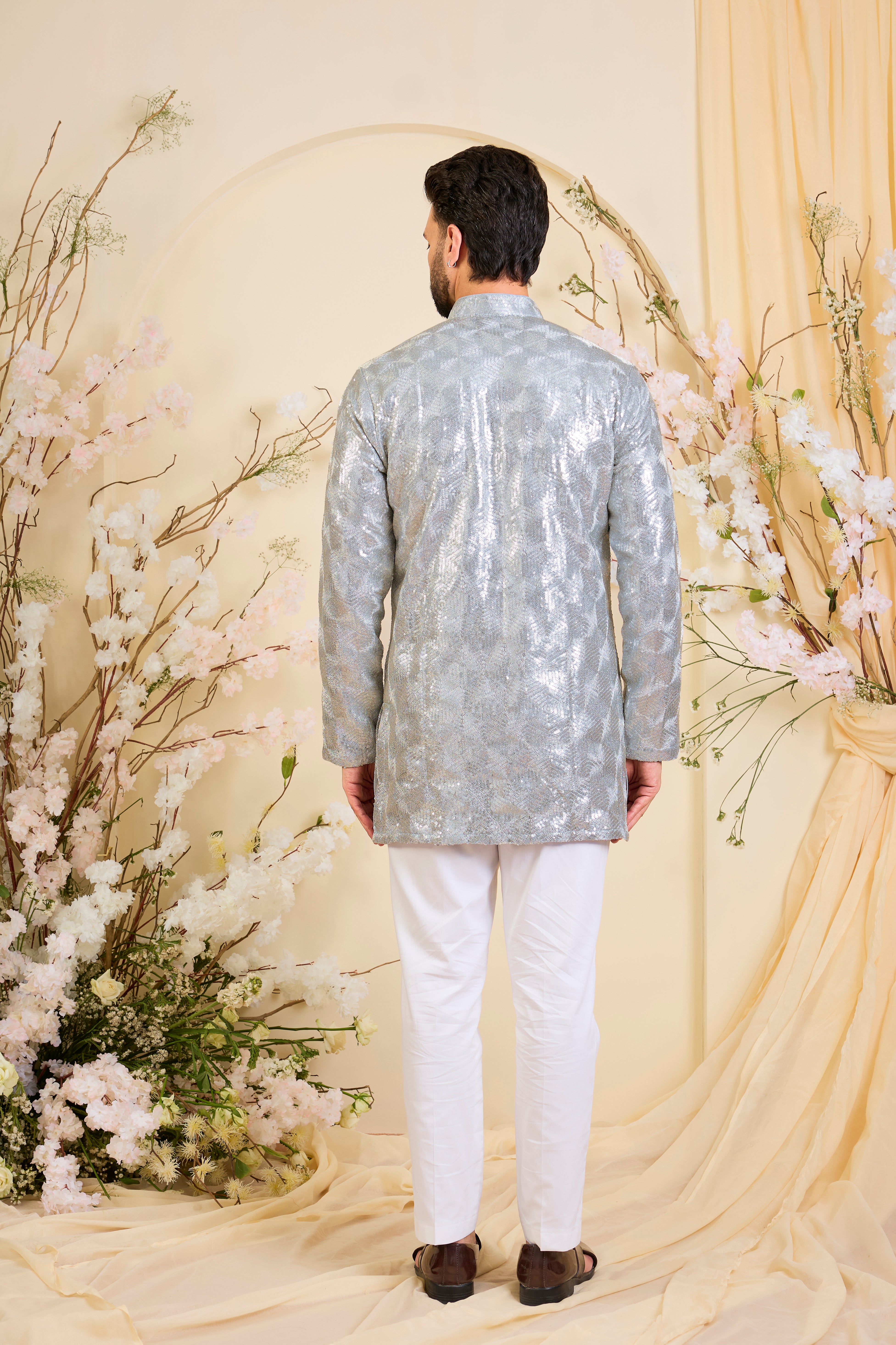 A luminous silver short kurta encrusted with dense, zari-like sequin work, delivering intense shine and intricate, high-impact detailing. Made to stand out.