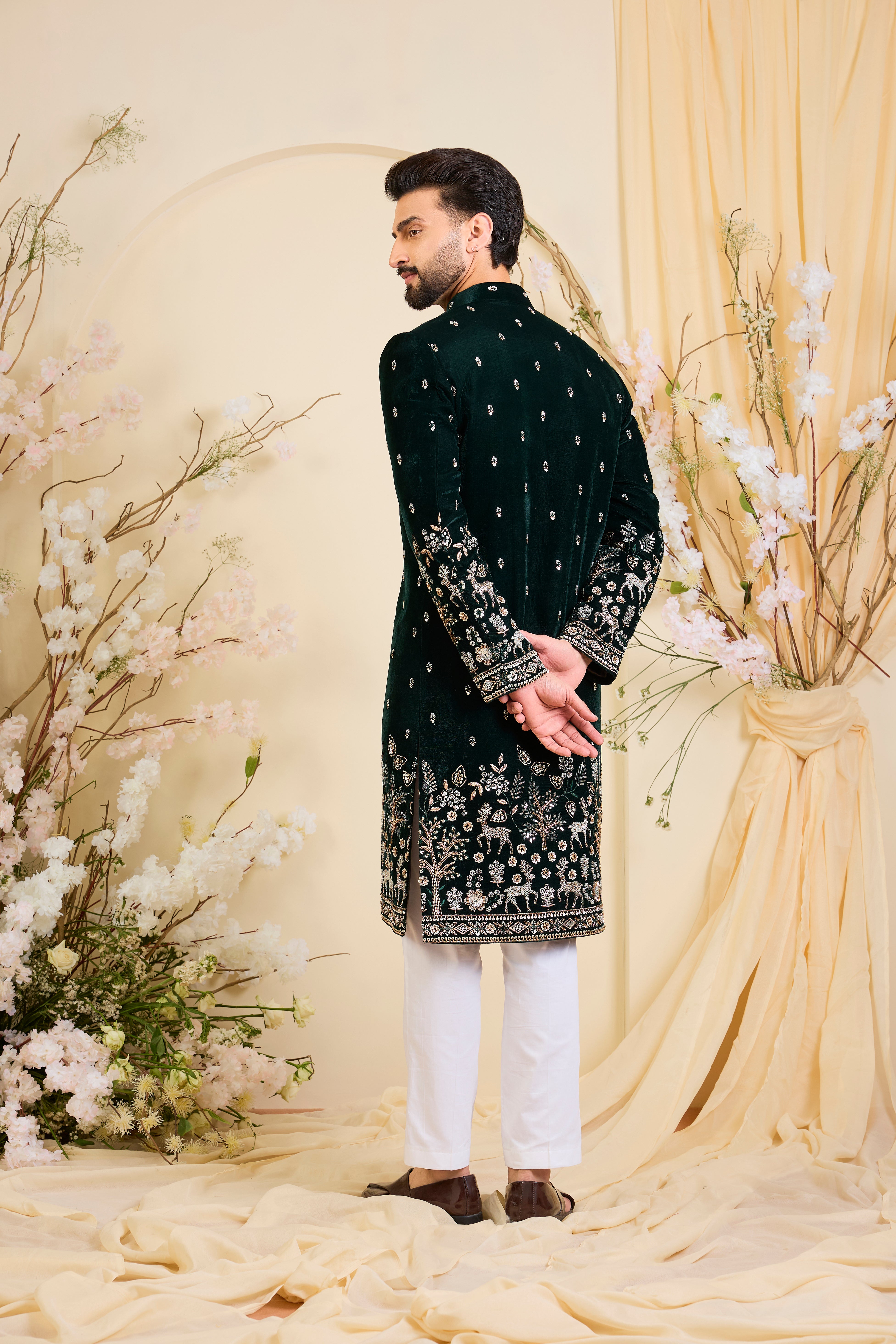 An opulent bottle green sherwani, intricately hand-embroidered with dense cut dana work and elaborate flora-fauna motifs, exuding regal depth and grand sophistication.