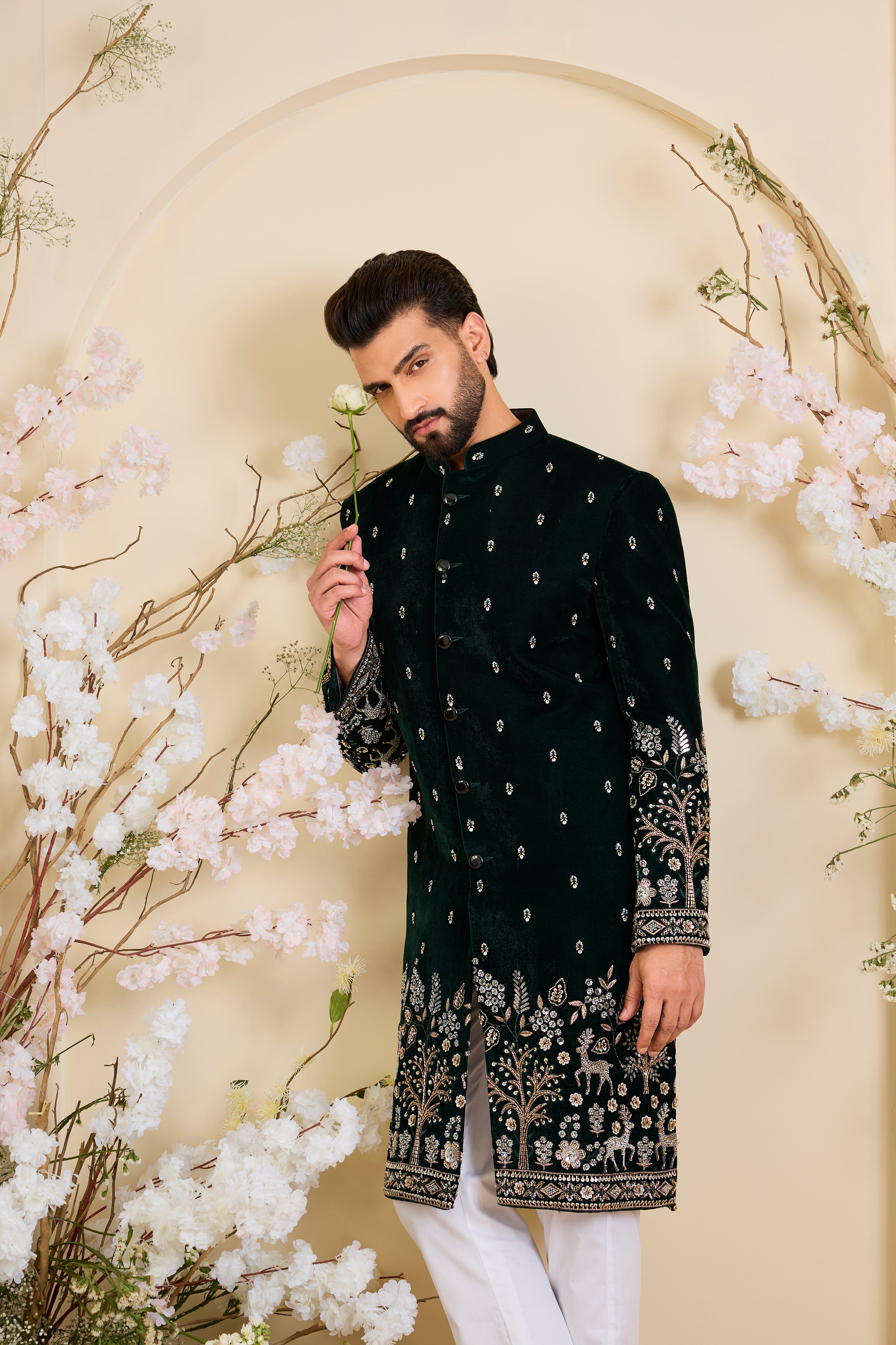 An opulent bottle green sherwani, intricately hand-embroidered with dense cut dana work and elaborate flora-fauna motifs, exuding regal depth and grand sophistication.