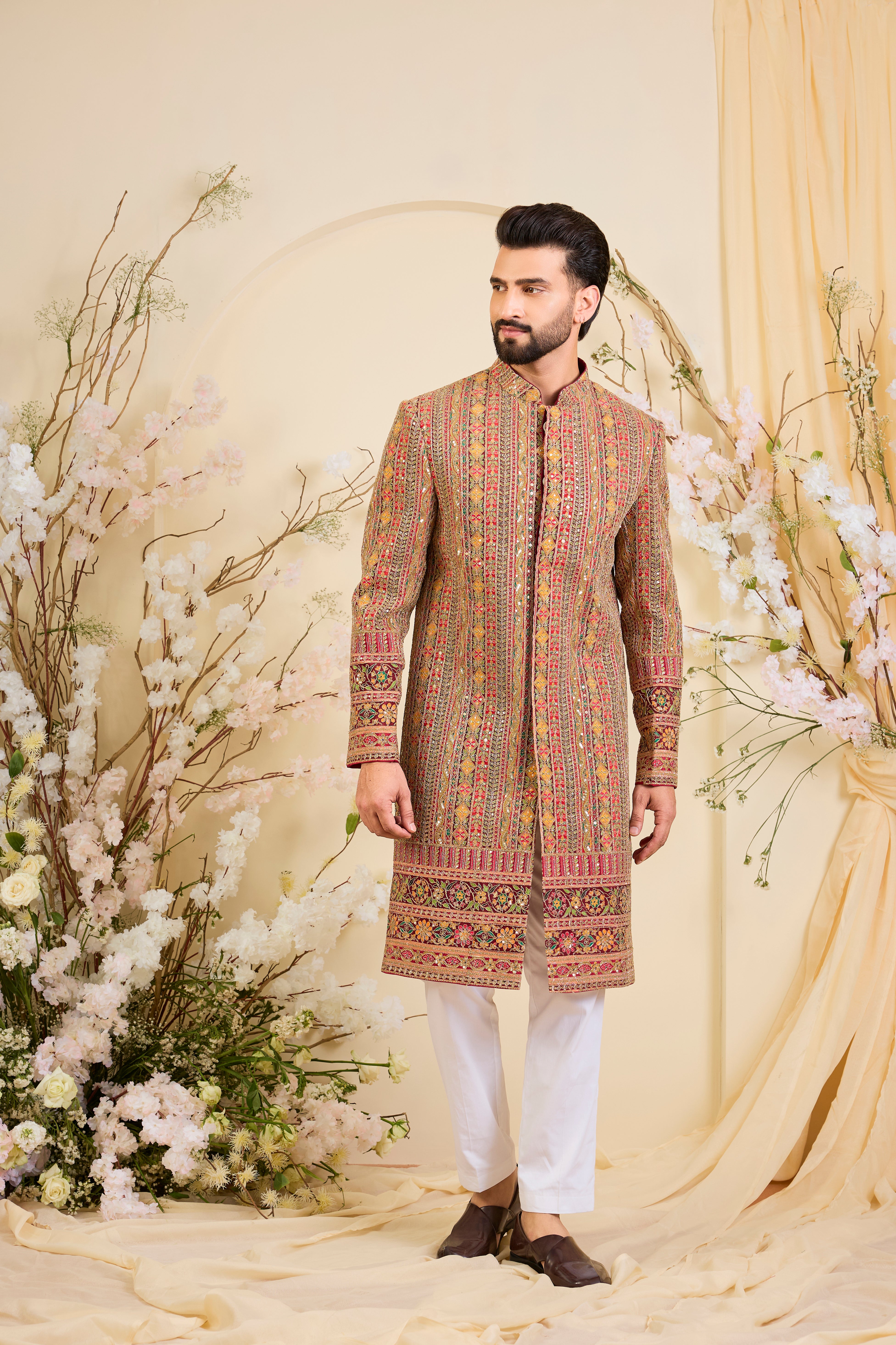 Pink base sherwani with heavy zari embroidery, intricate sequins, and multicolour prints, crafted for bold, opulent, statement-making occasions.