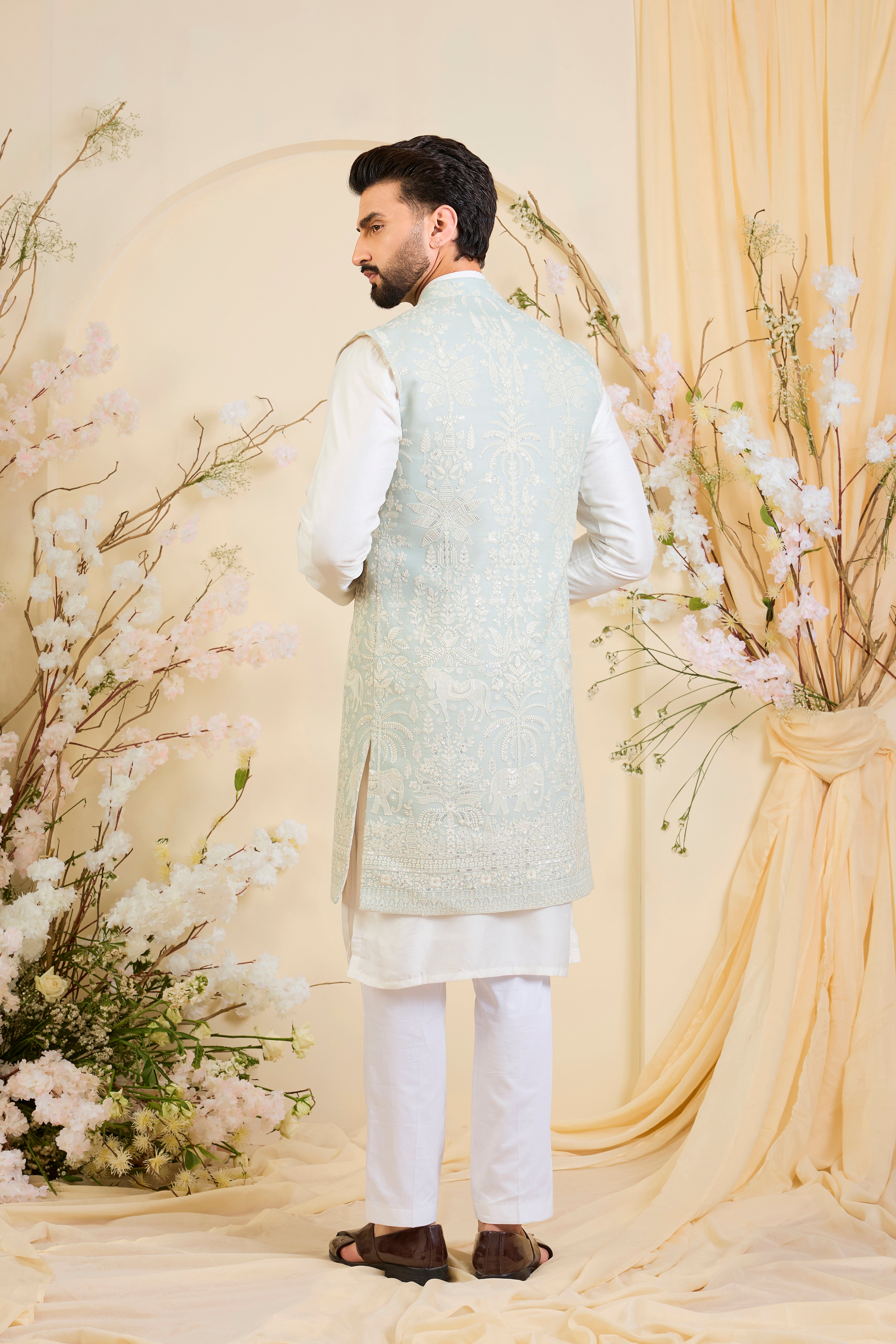 Blue sequined long jacket with ivory threadwork and intricate flora-fauna embroidery, crafted for luminous, refined, statement-making elegance.