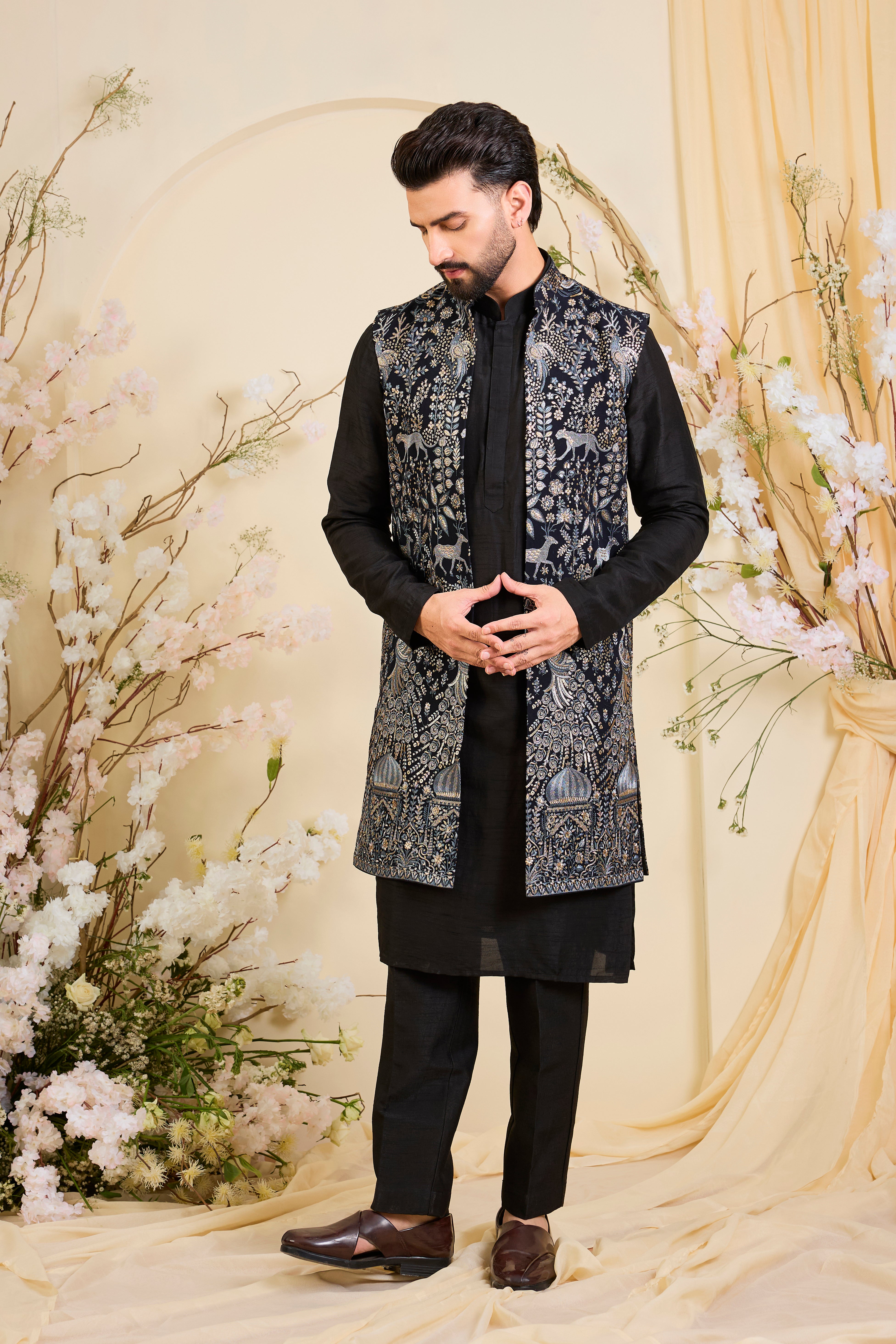 Blue long open jacket with intricate zari work, sequin detailing, and Mughal darbar scenes with flora-fauna motifs, delivering a grand couture statement.