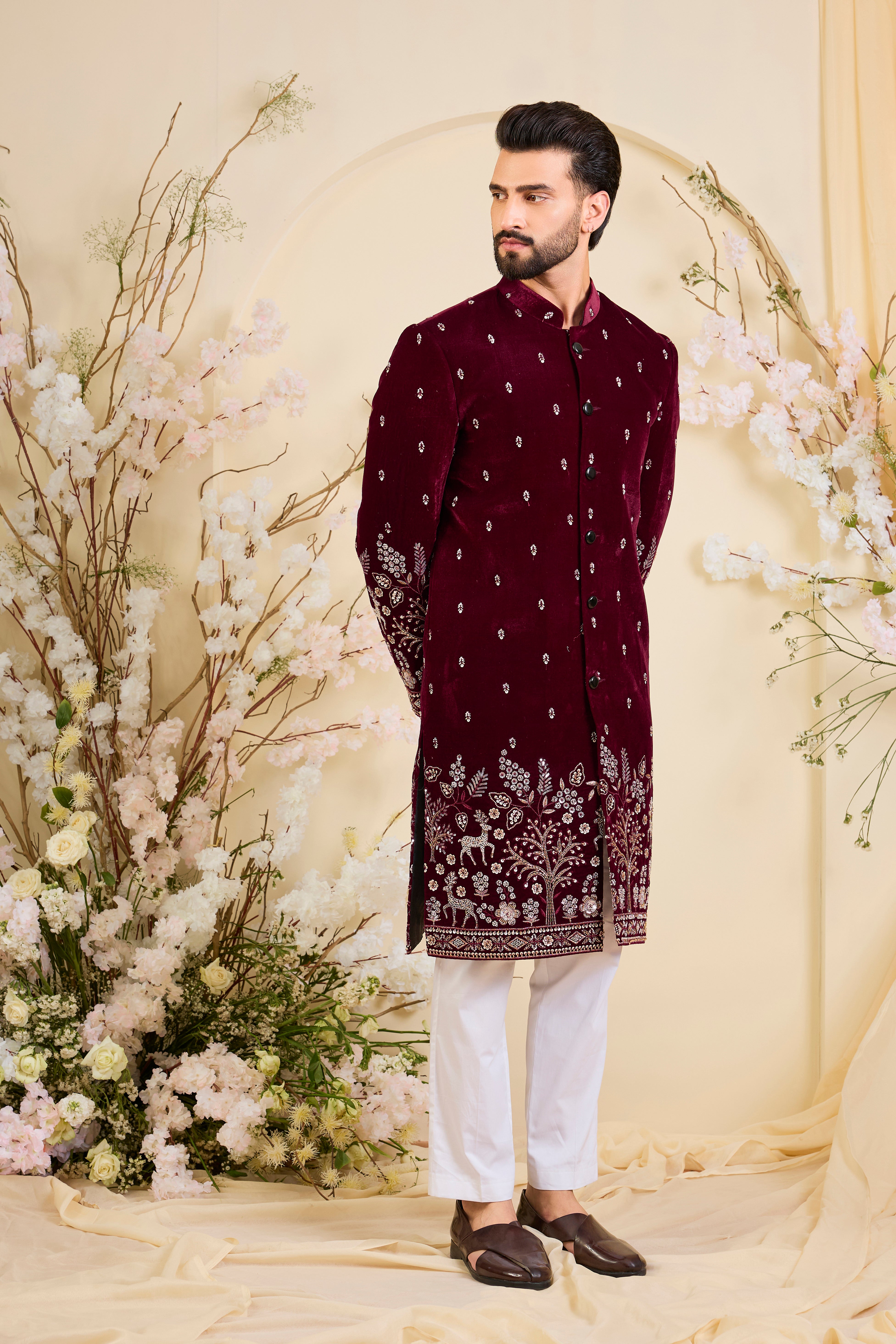 An opulent maroon sherwani, intricately hand-embroidered with dense cut dana work and elaborate flora-fauna motifs, exuding regal depth and grand sophistication.