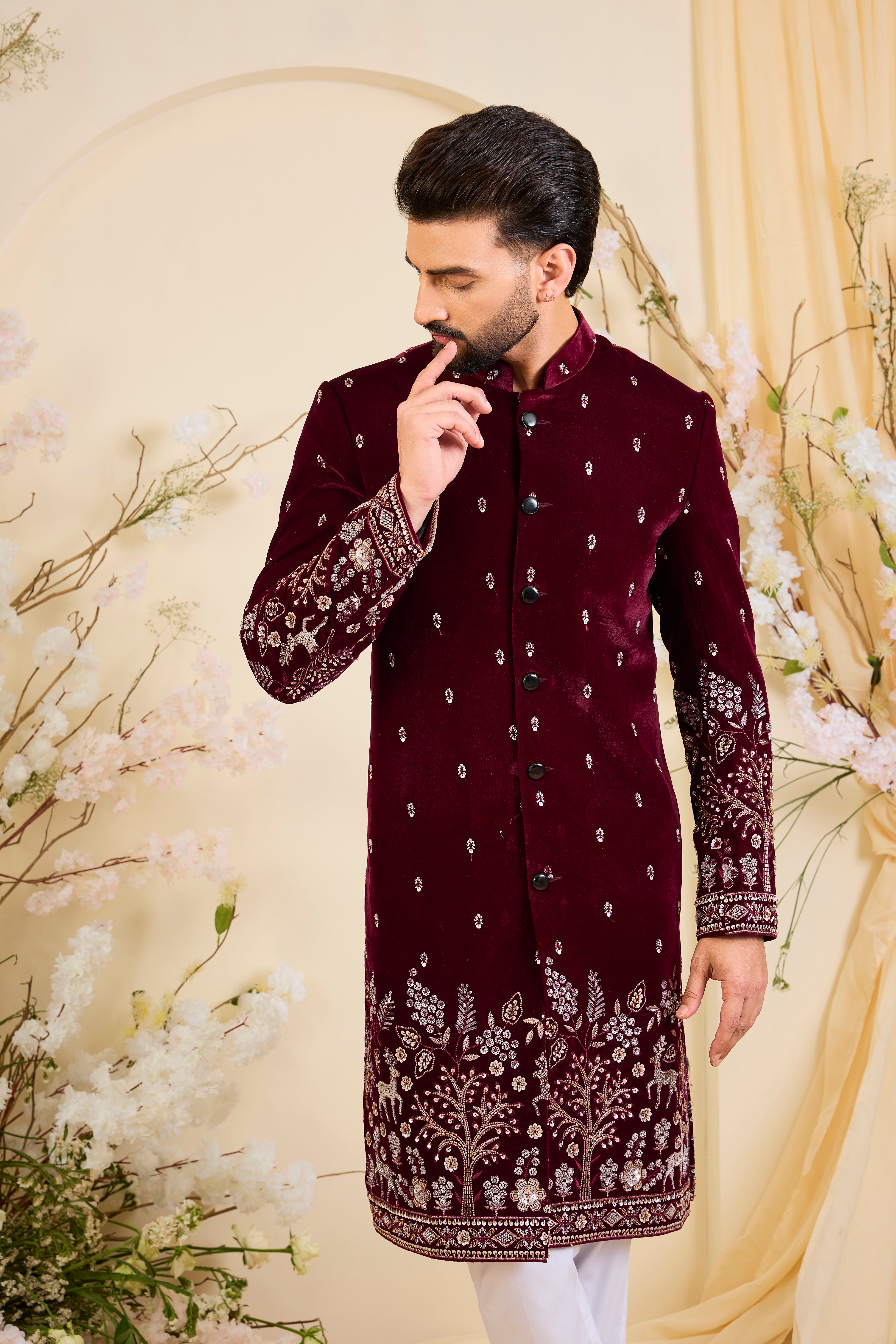 An opulent maroon sherwani, intricately hand-embroidered with dense cut dana work and elaborate flora-fauna motifs, exuding regal depth and grand sophistication.
