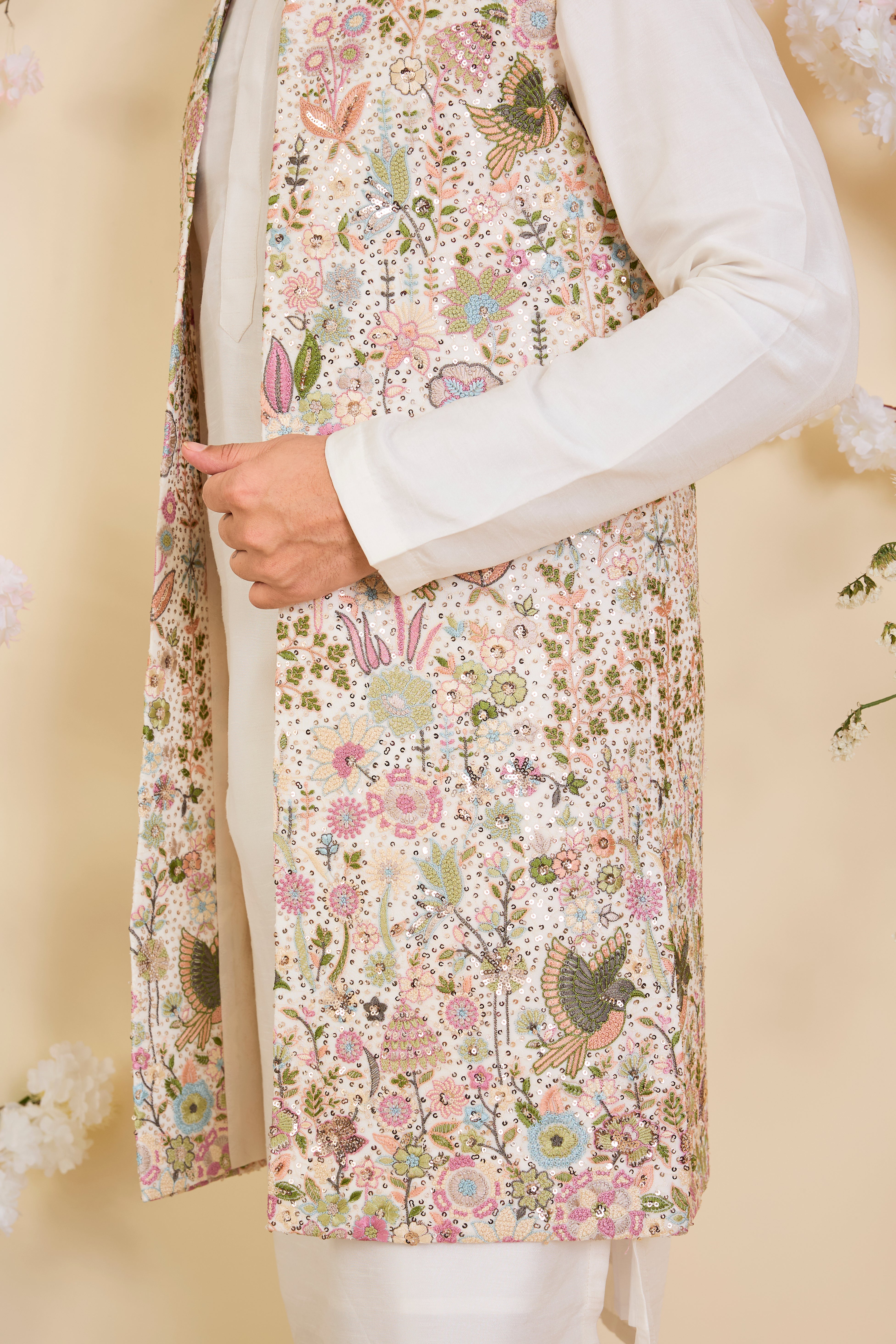 White long open jacket with intricate sequin work and detailed flora-fauna motifs, offering a luminous, richly layered couture statement.