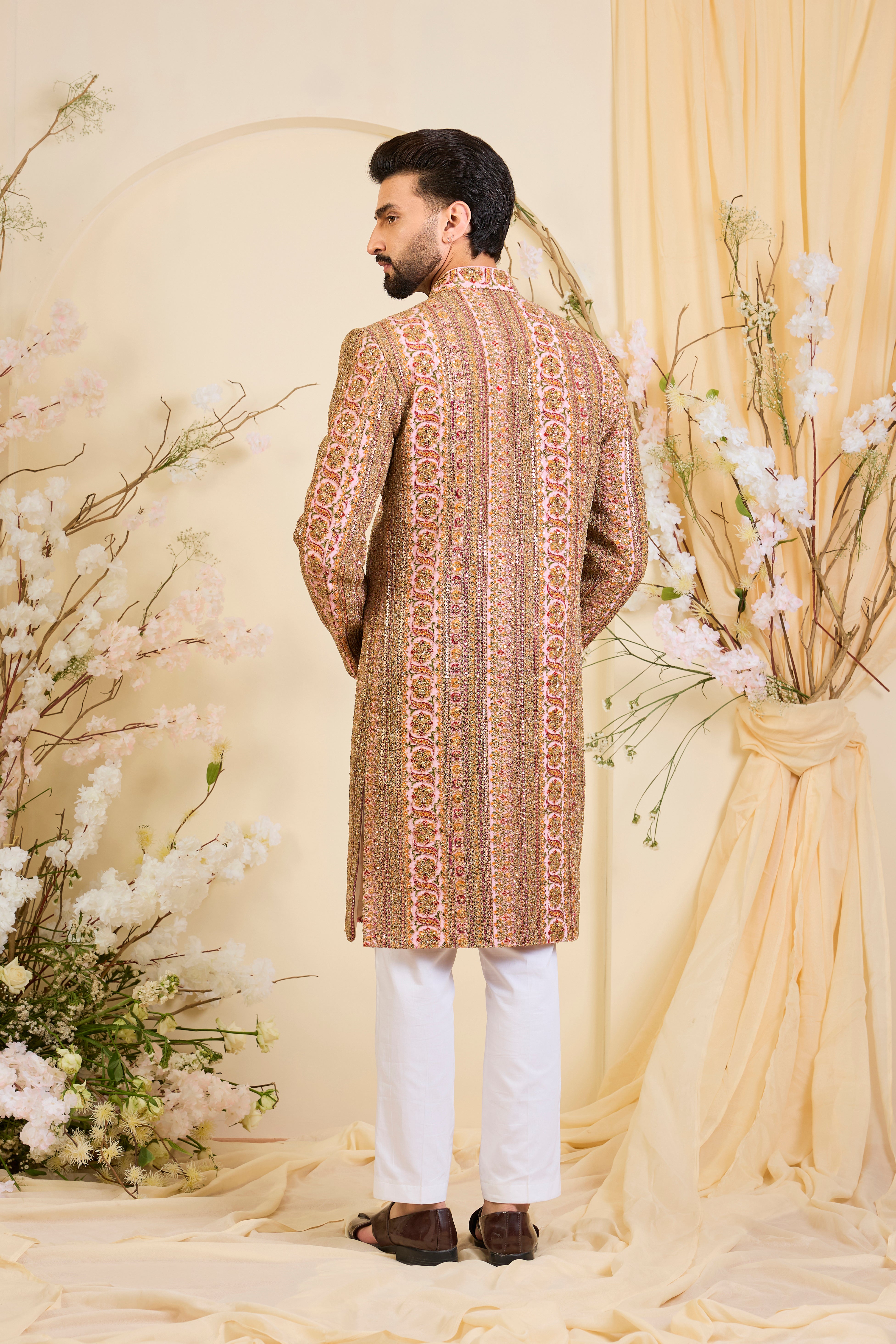 Pink base sherwani with heavy zari embroidery, intricate sequins, and multicolour prints, crafted for bold, opulent, statement-making occasions.