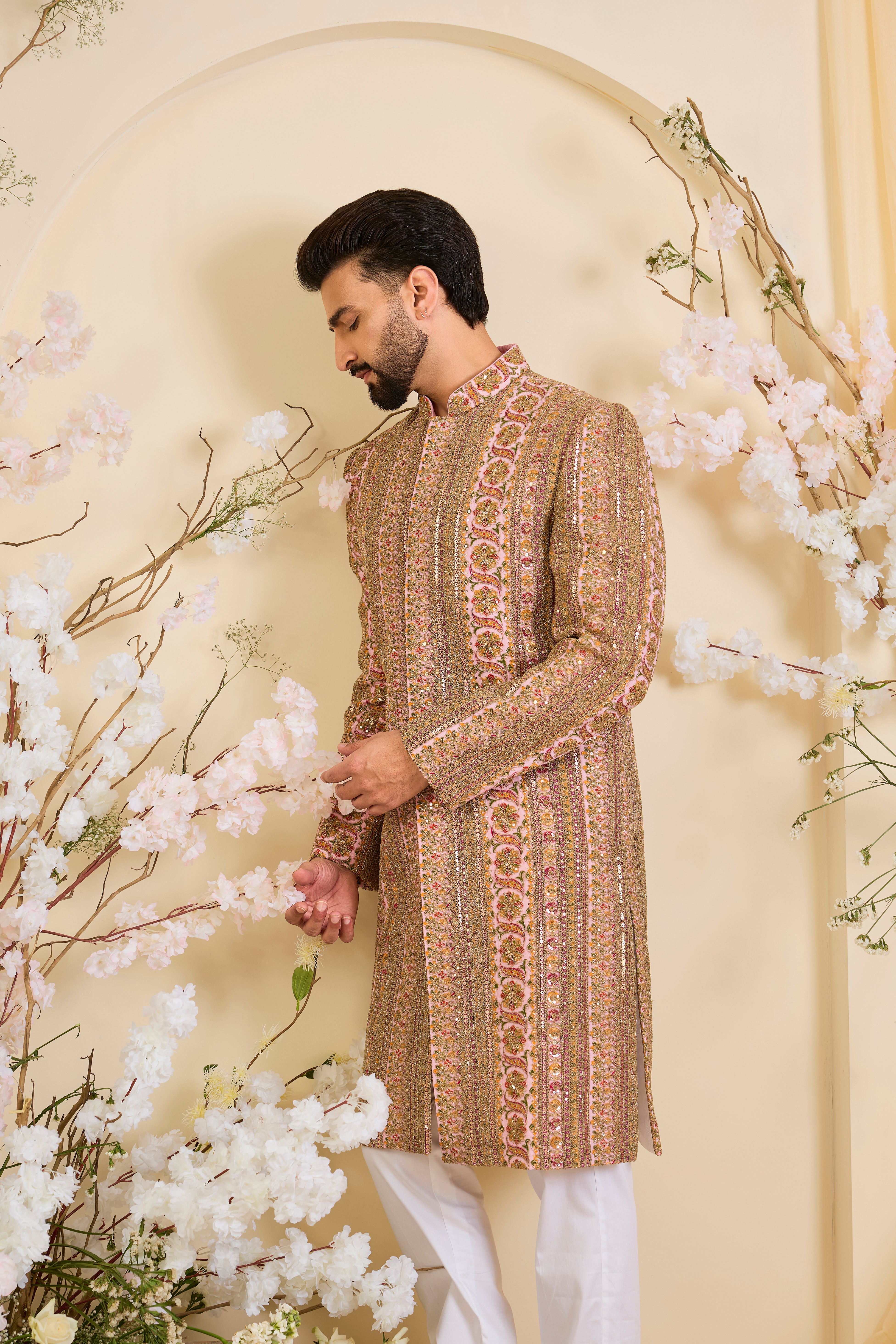 Pink base sherwani with heavy zari embroidery, intricate sequins, and multicolour prints, crafted for bold, opulent, statement-making occasions.