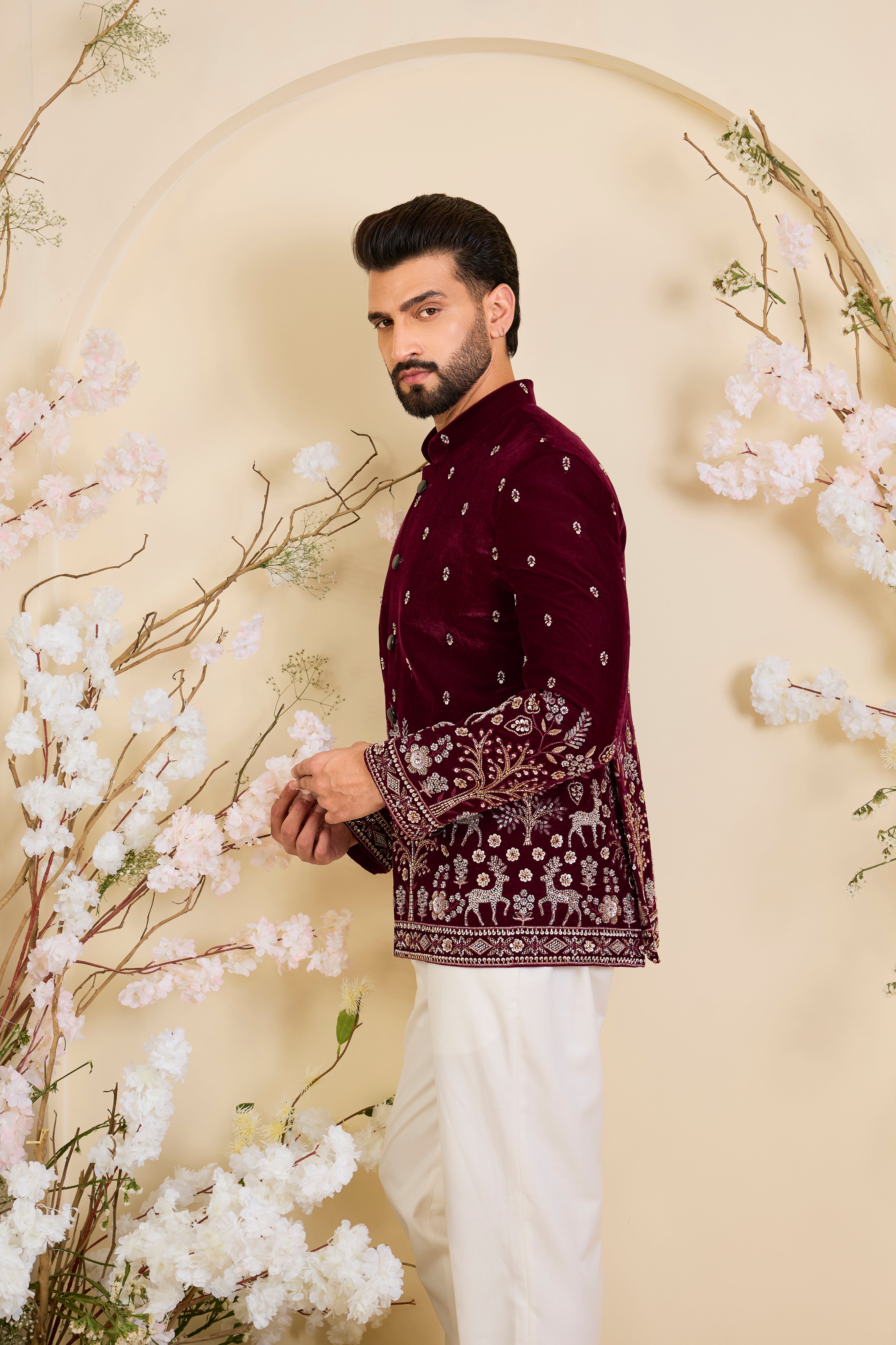 An opulent maroon bandgala , intricately hand-embroidered with dense cut dana work and elaborate flora-fauna motifs, exuding regal depth and grand sophistication.