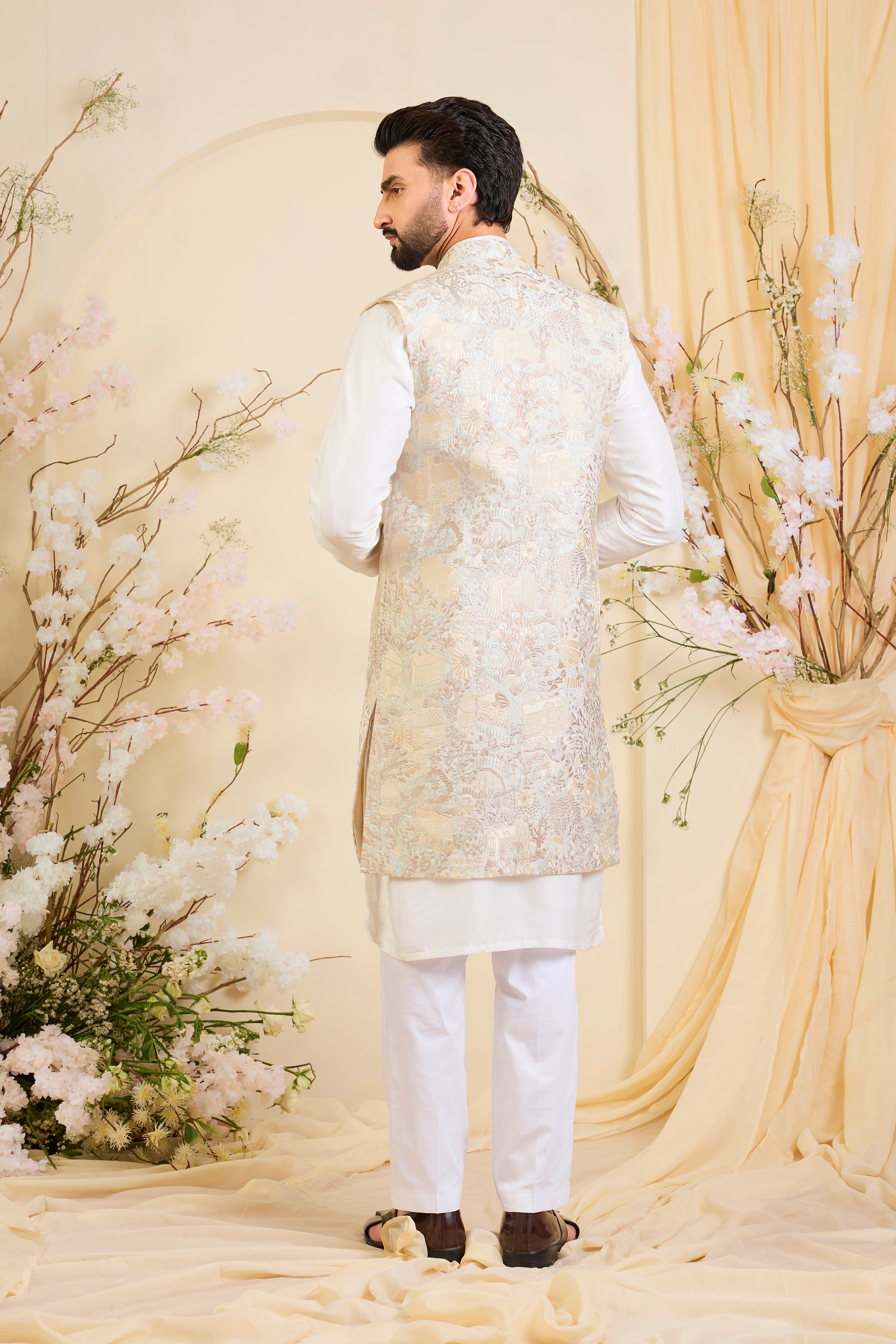 Beige-cream long open jacket with intricate flora-fauna embroidery and dense threadwork, offering a refined, richly textured couture statement.