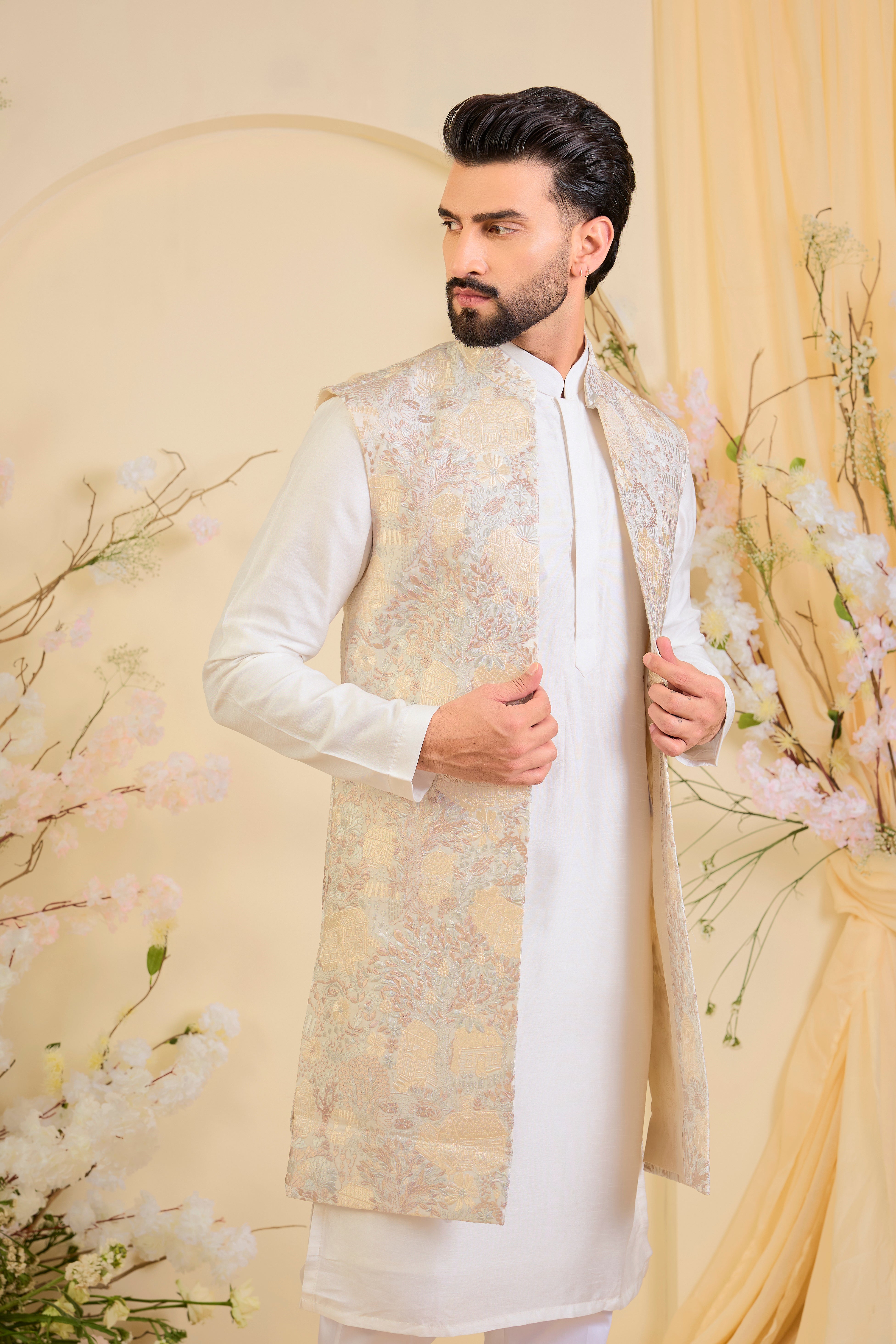 Beige-cream long open jacket with intricate flora-fauna embroidery and dense threadwork, offering a refined, richly textured couture statement.
