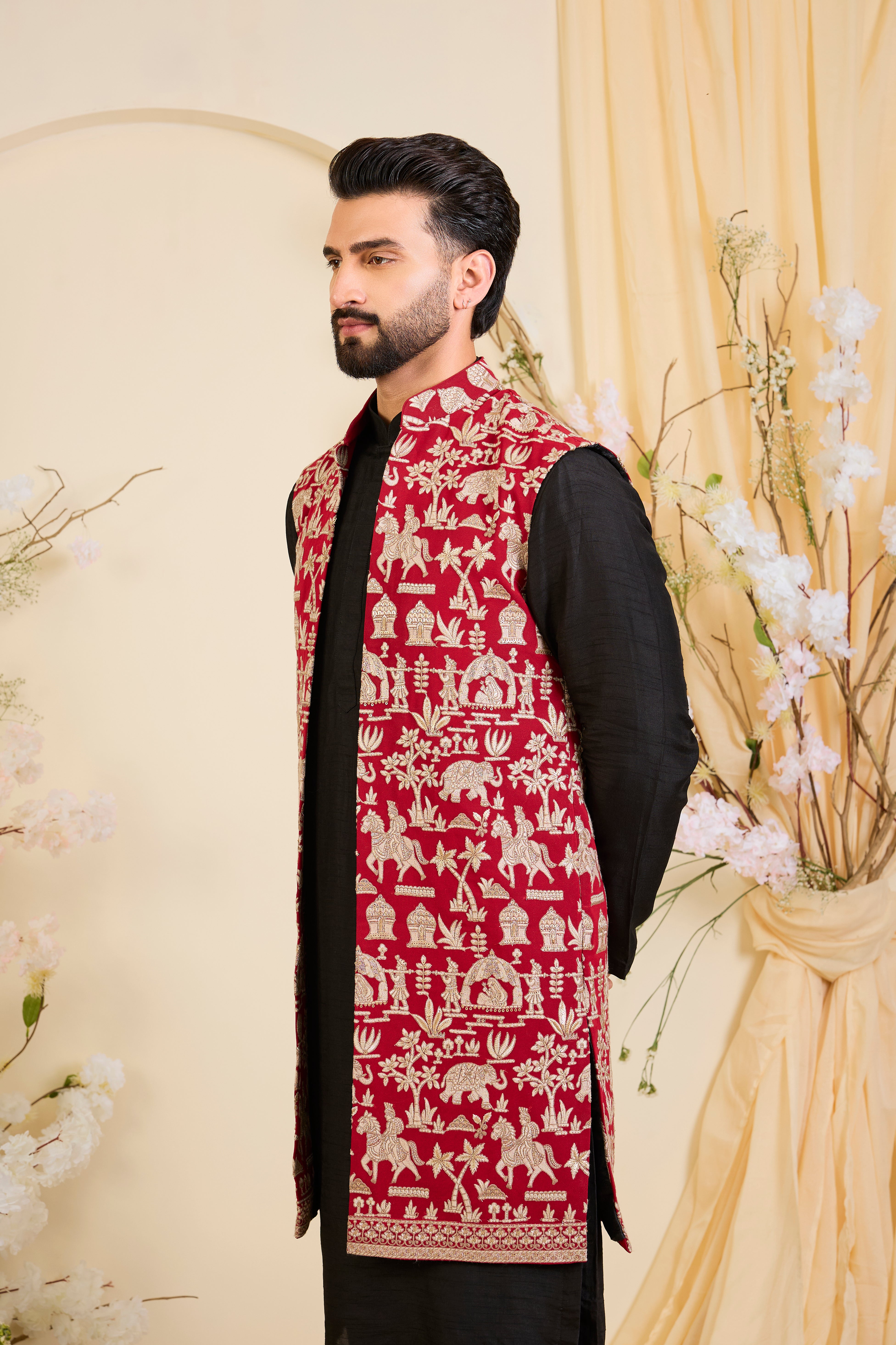 Red/pink long open jacket with intricate zari work, sequin detailing, and Mughal-era embroidery, delivering a richly layered, regal couture statement.