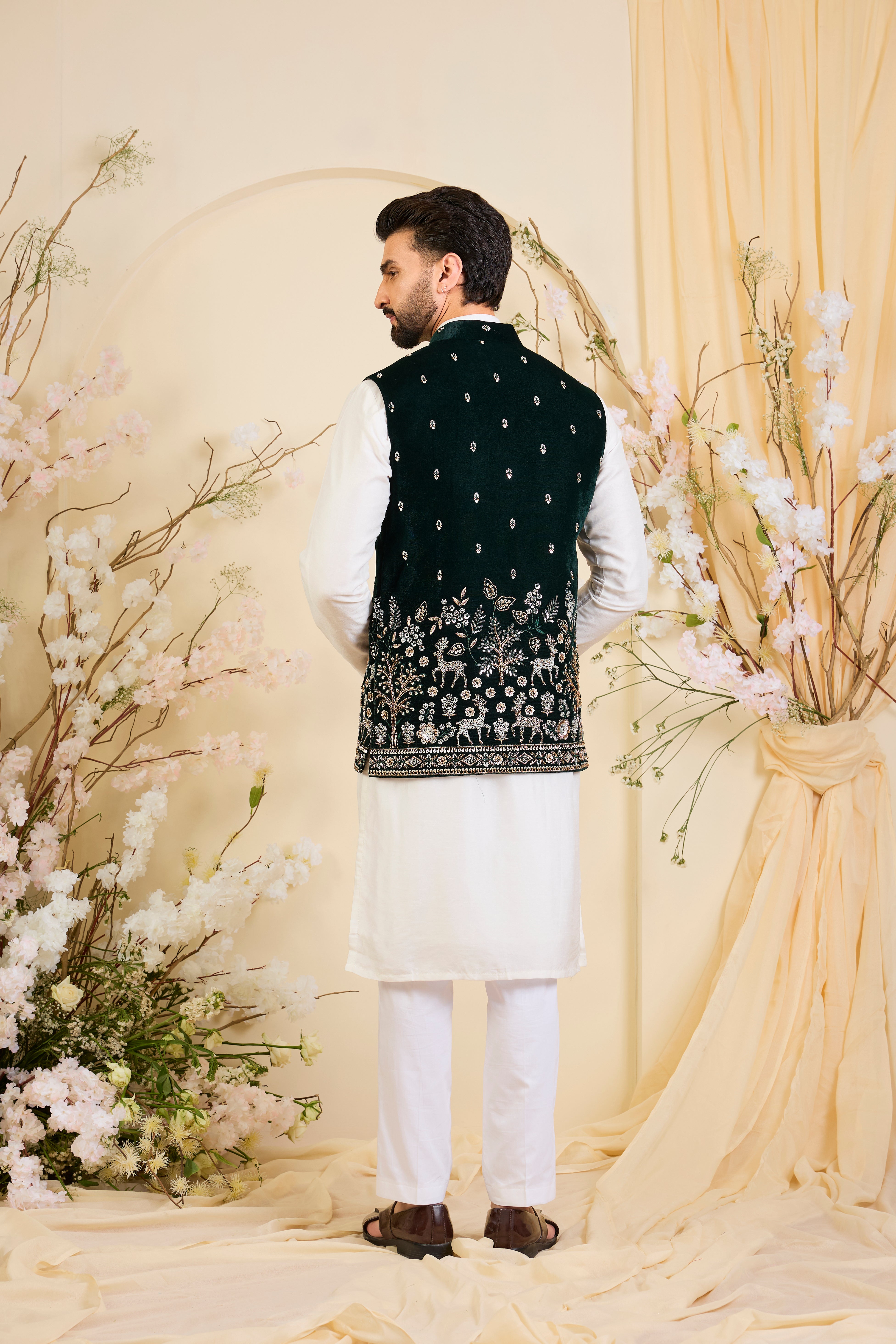 An opulent bottle green nehru jacket , intricately hand-embroidered with dense cut dana work and elaborate flora-fauna motifs, exuding regal depth and grand sophistication.