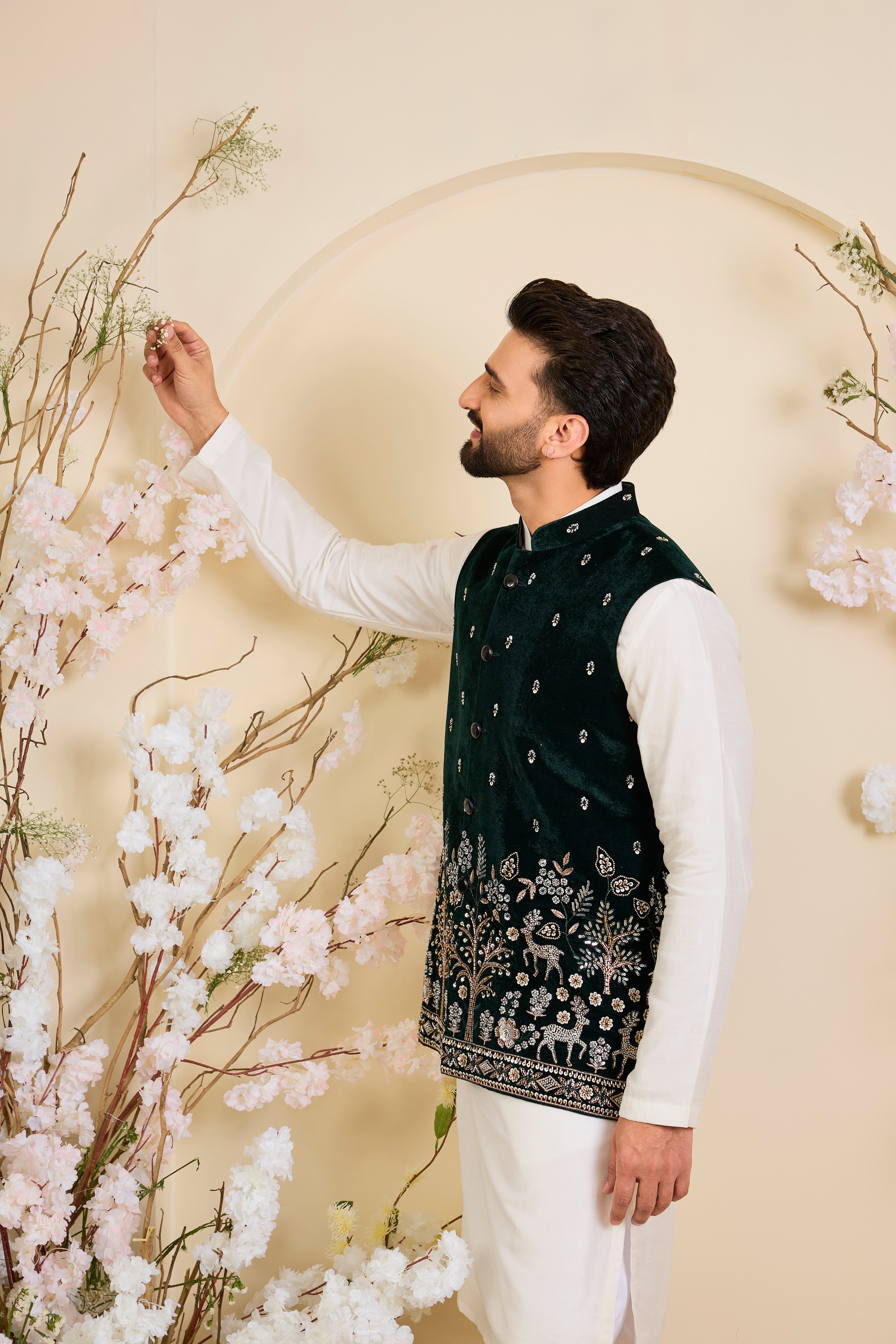 An opulent bottle green nehru jacket , intricately hand-embroidered with dense cut dana work and elaborate flora-fauna motifs, exuding regal depth and grand sophistication.