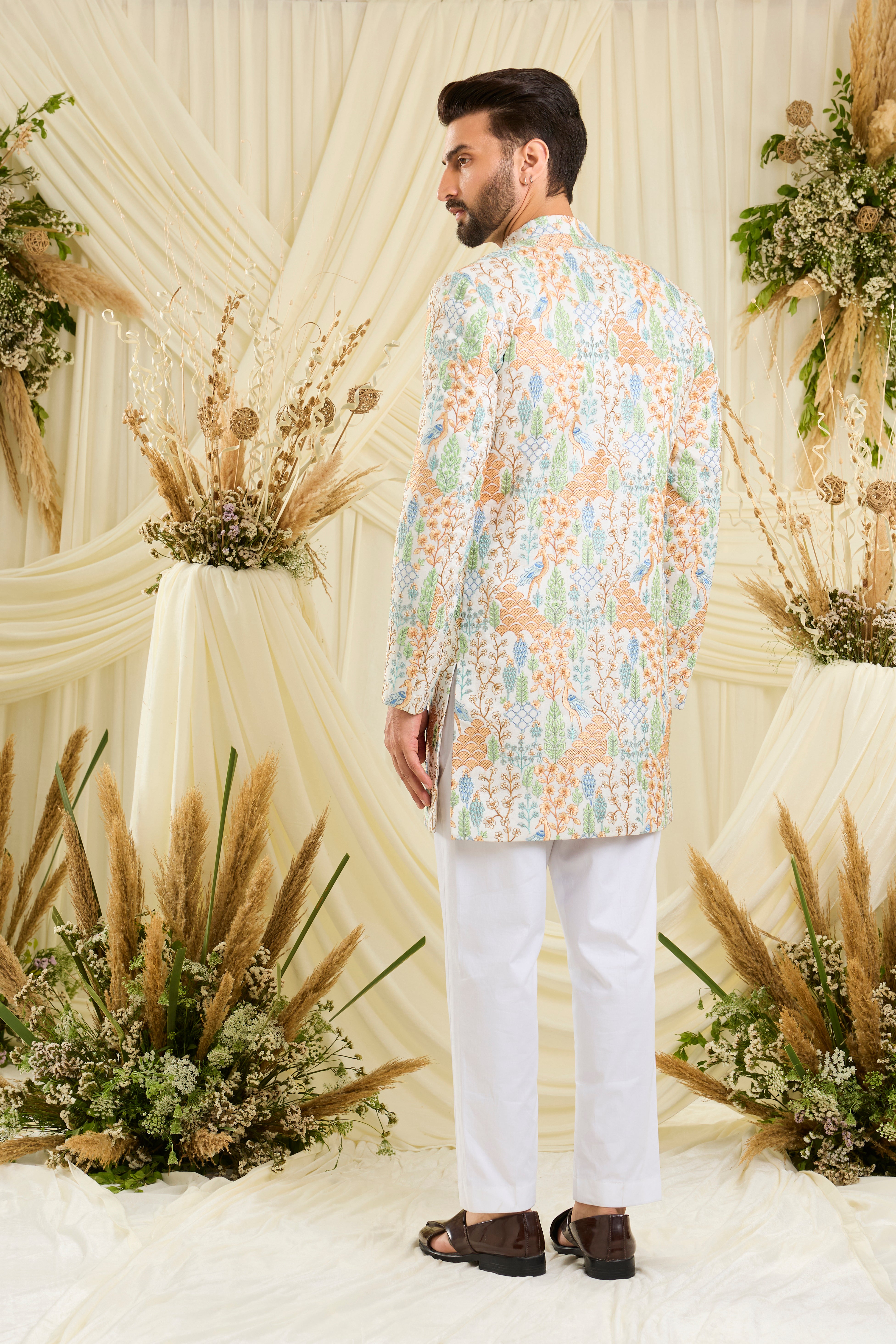 Ivory short sherwani with heavy flora-fauna embroidery, multicolour threadwork, and delicate sequins for a richly detailed, luxe statement.