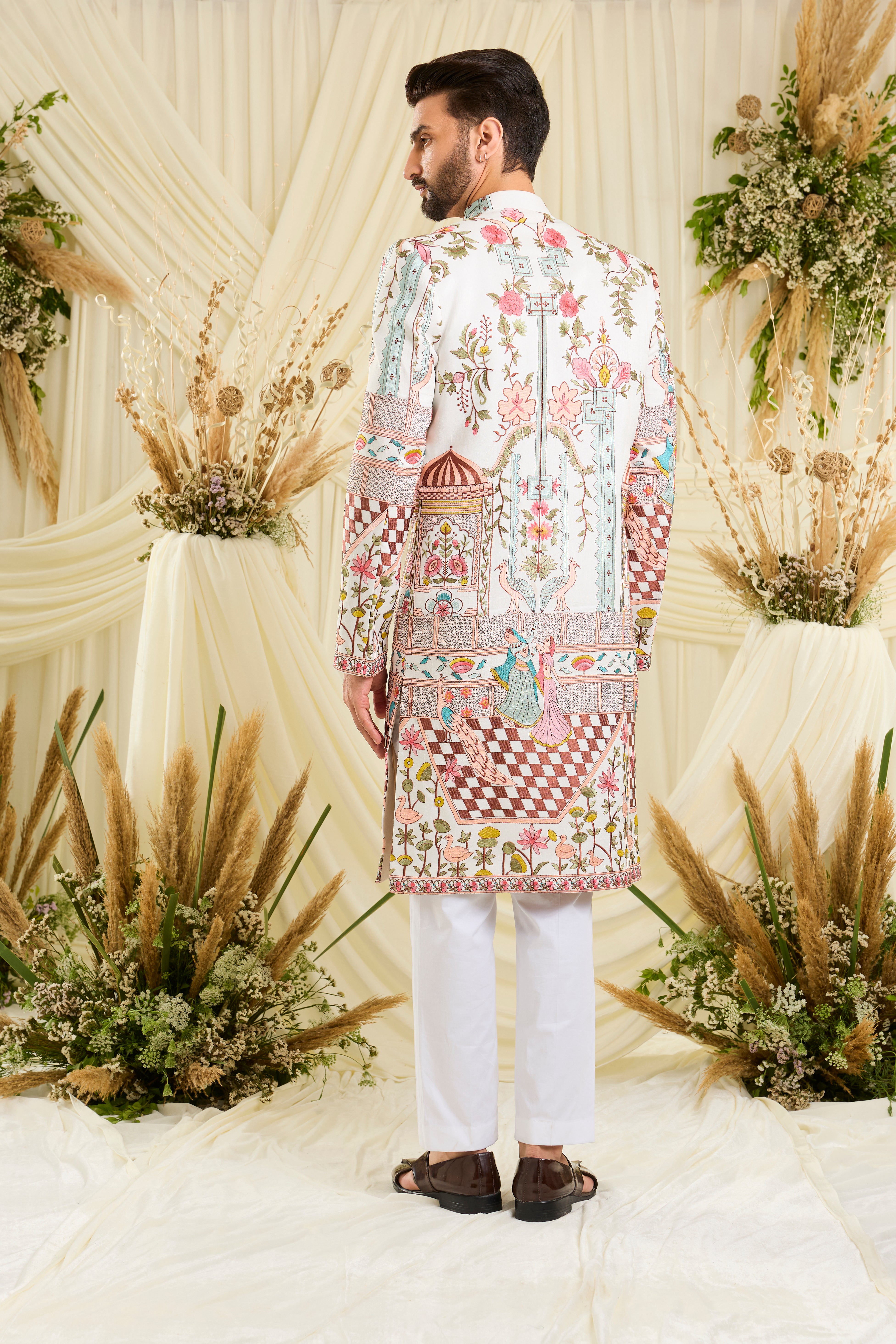 Opulent silk sherwani with Mughal darbars, peacocks, florals, and dancing royals — a masterpiece of imperial artistry.