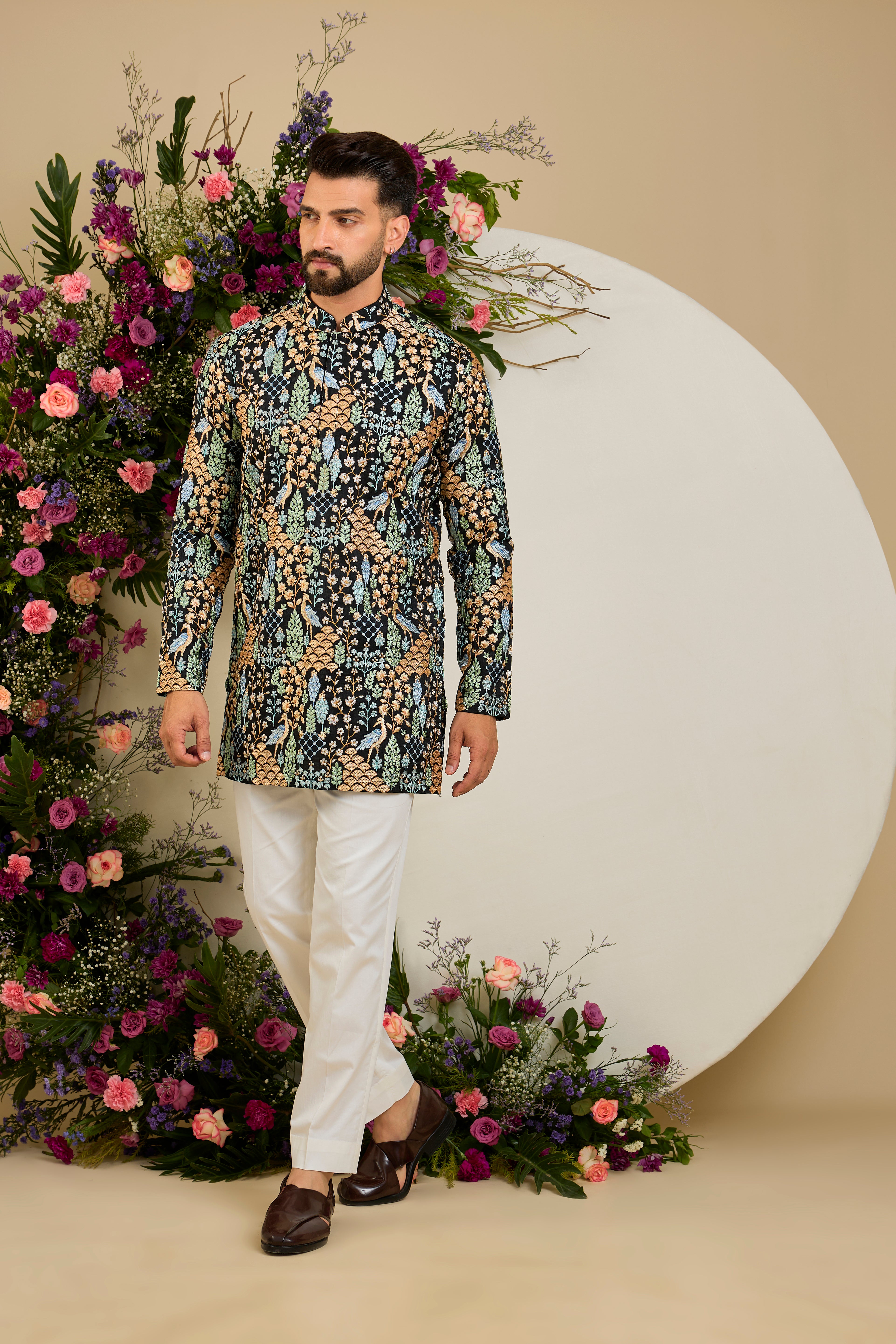 Black short kurta with tropical flora and fauna embroidery, vibrant threadwork, and delicate sequins for refined formal elegance.