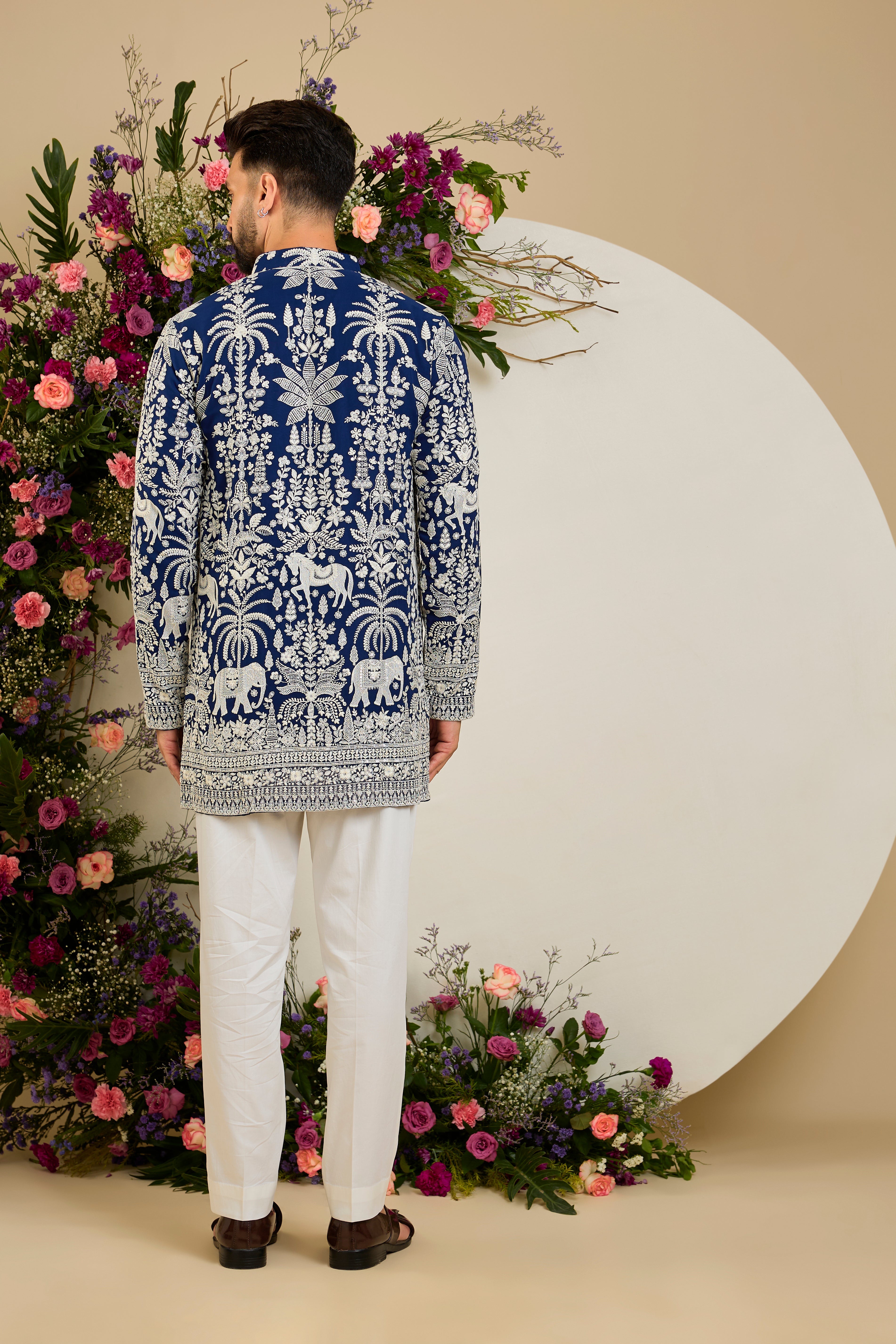 Royal blue short kurta with tropical flora and fauna embroidery, ivory threadwork, and delicate sequin detailing for refined occasion wear.