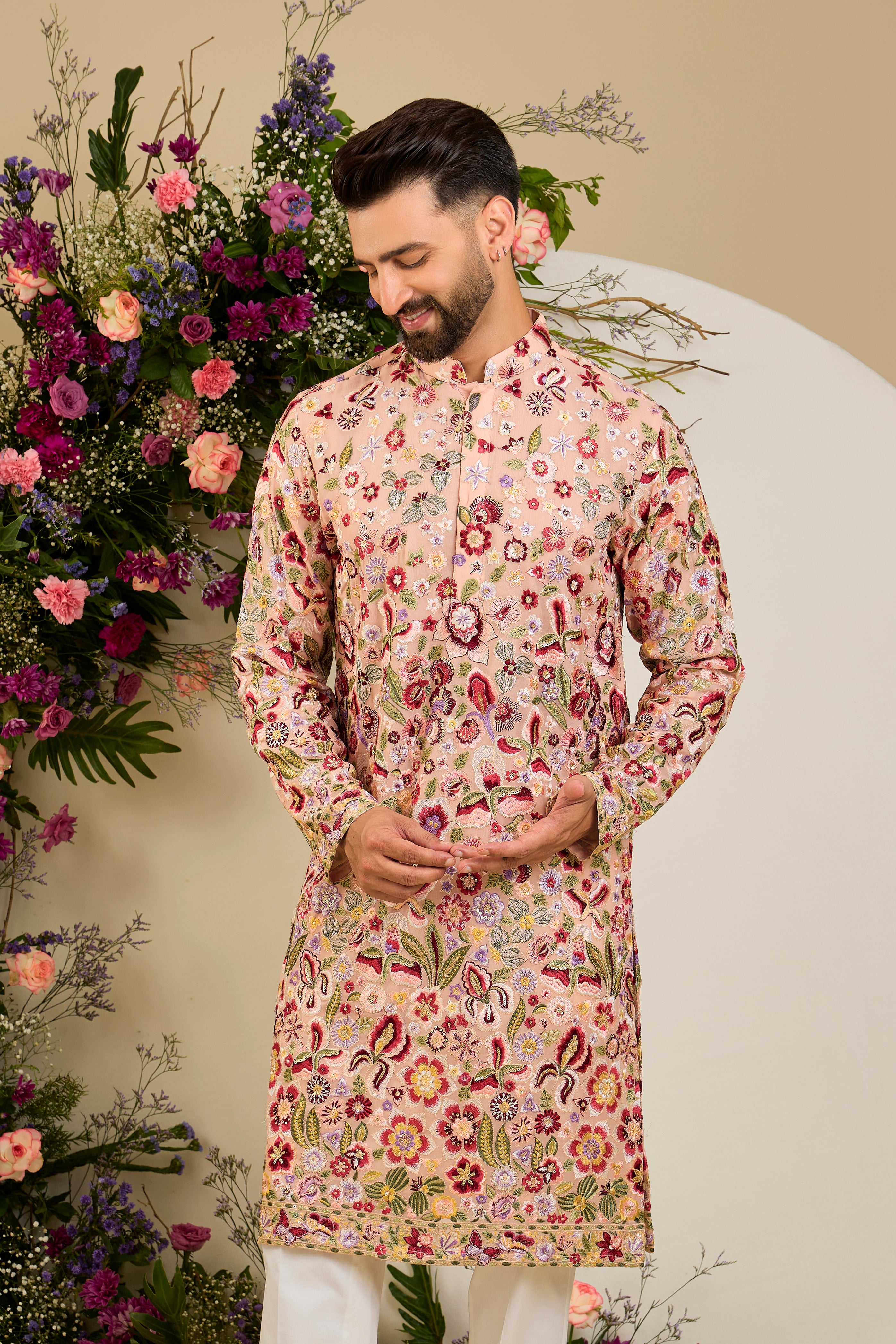 Blush peach pastel kurta with a vibrant floral backdrop, multi-coloured thread embroidery, and delicate sequin detailing for timeless elegance.