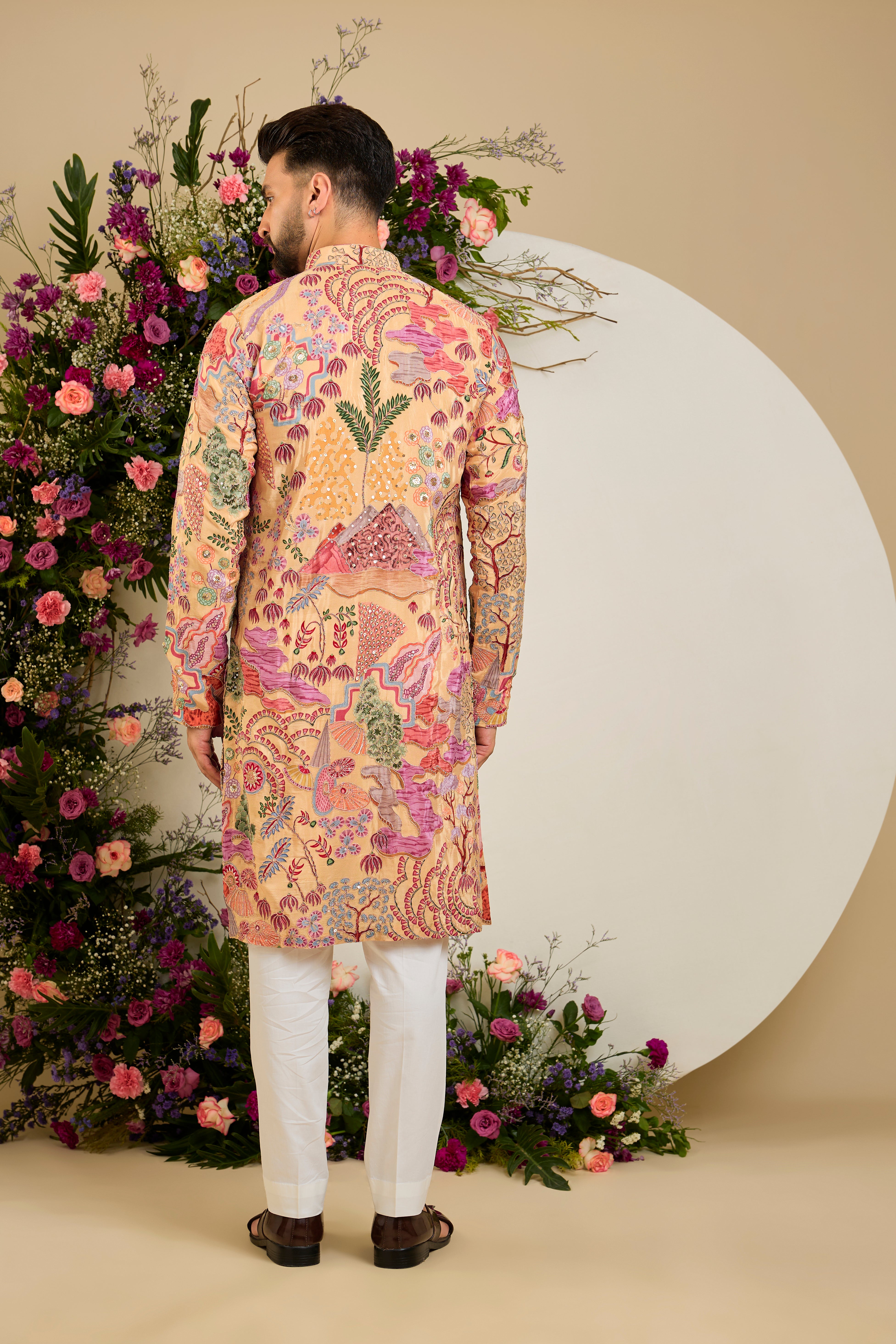 Tan peach crepe kurta with a botanical print, refined zari embroidery, and delicate sequin detailing for elevated occasion dressing.