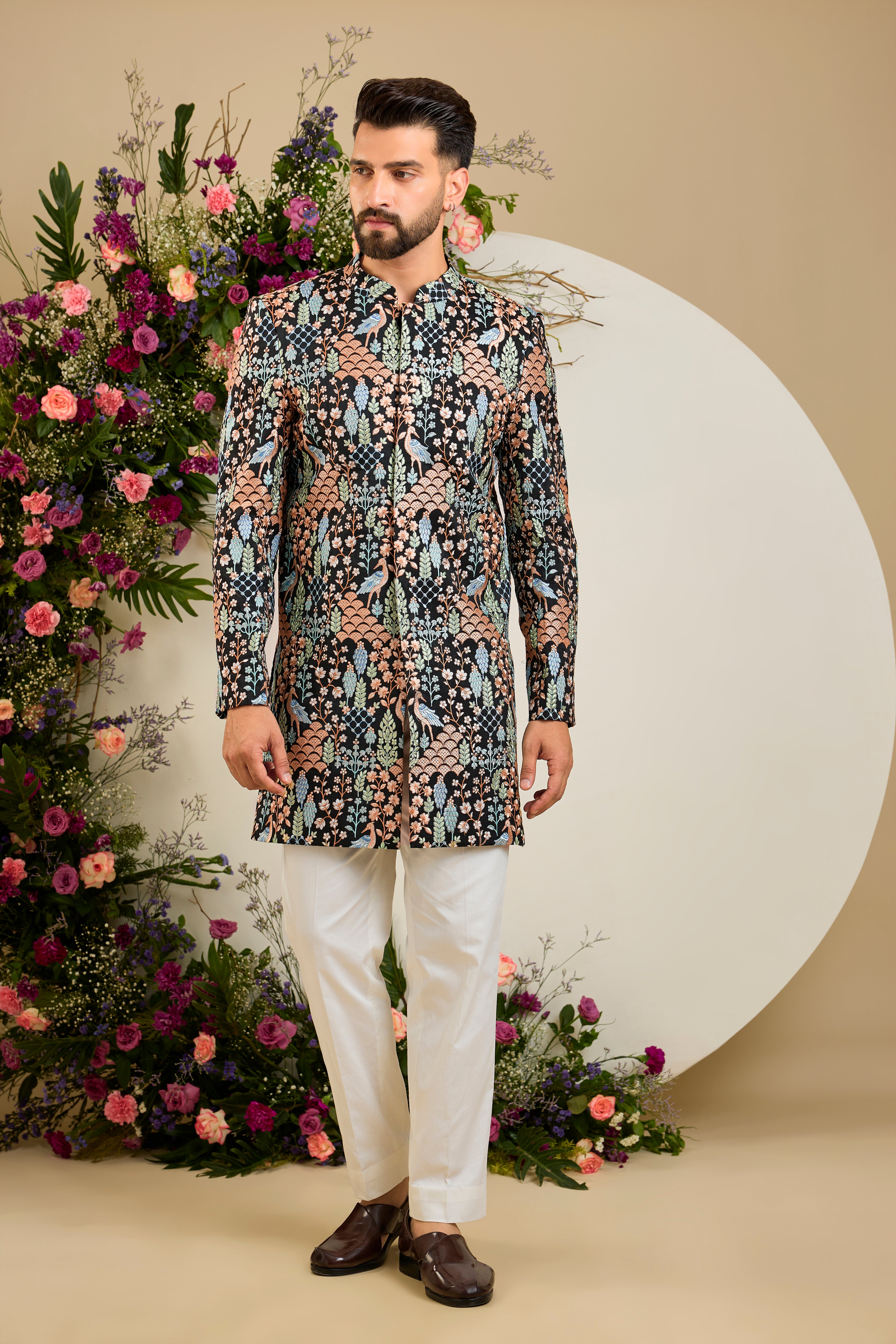 Black short sherwani with tropical flora and fauna embroidery, vibrant threadwork, and delicate sequins for refined formal elegance.