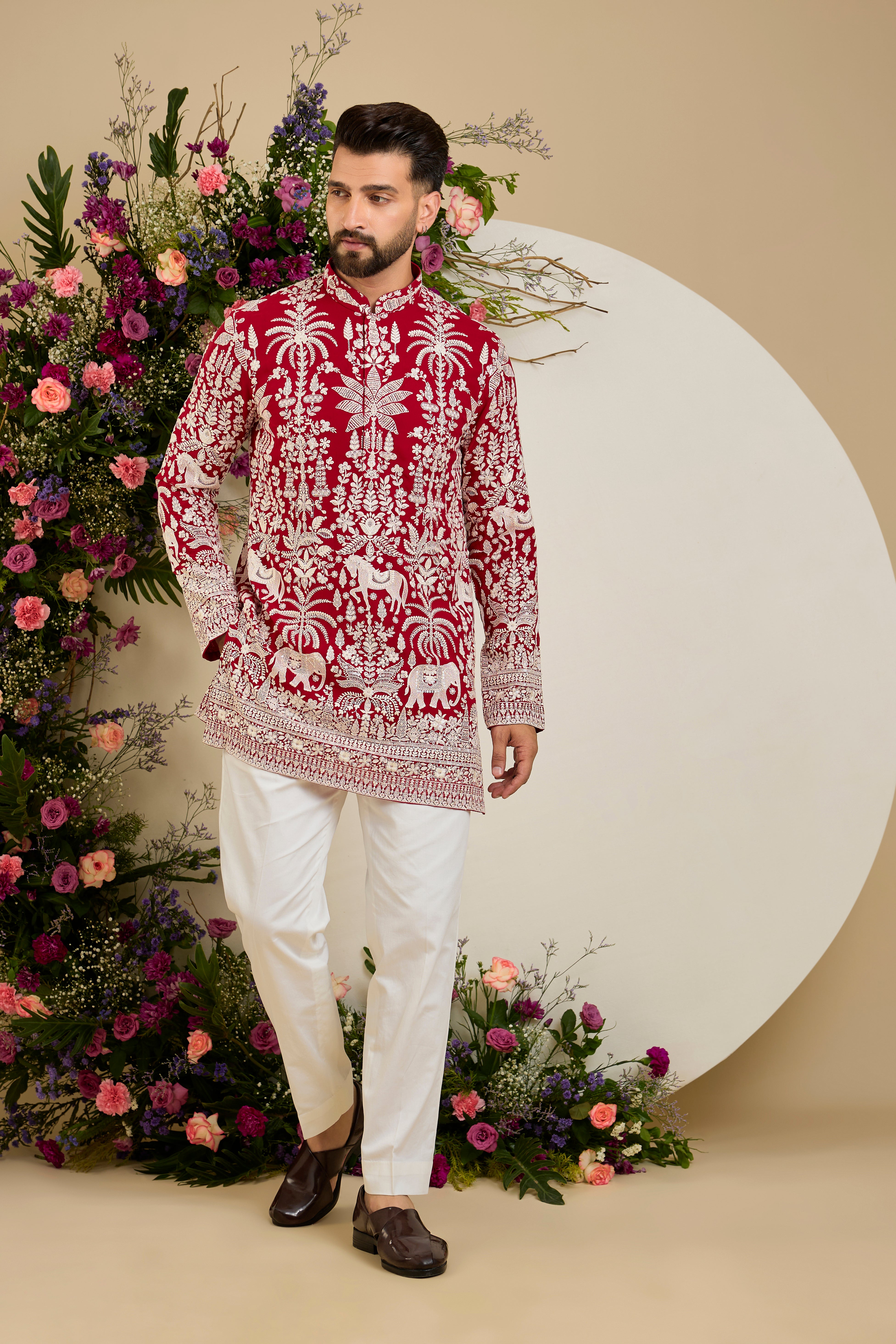 Red short kurta with tropical flora and fauna embroidery, ivory threadwork, and delicate sequin detailing for refined occasion wear.