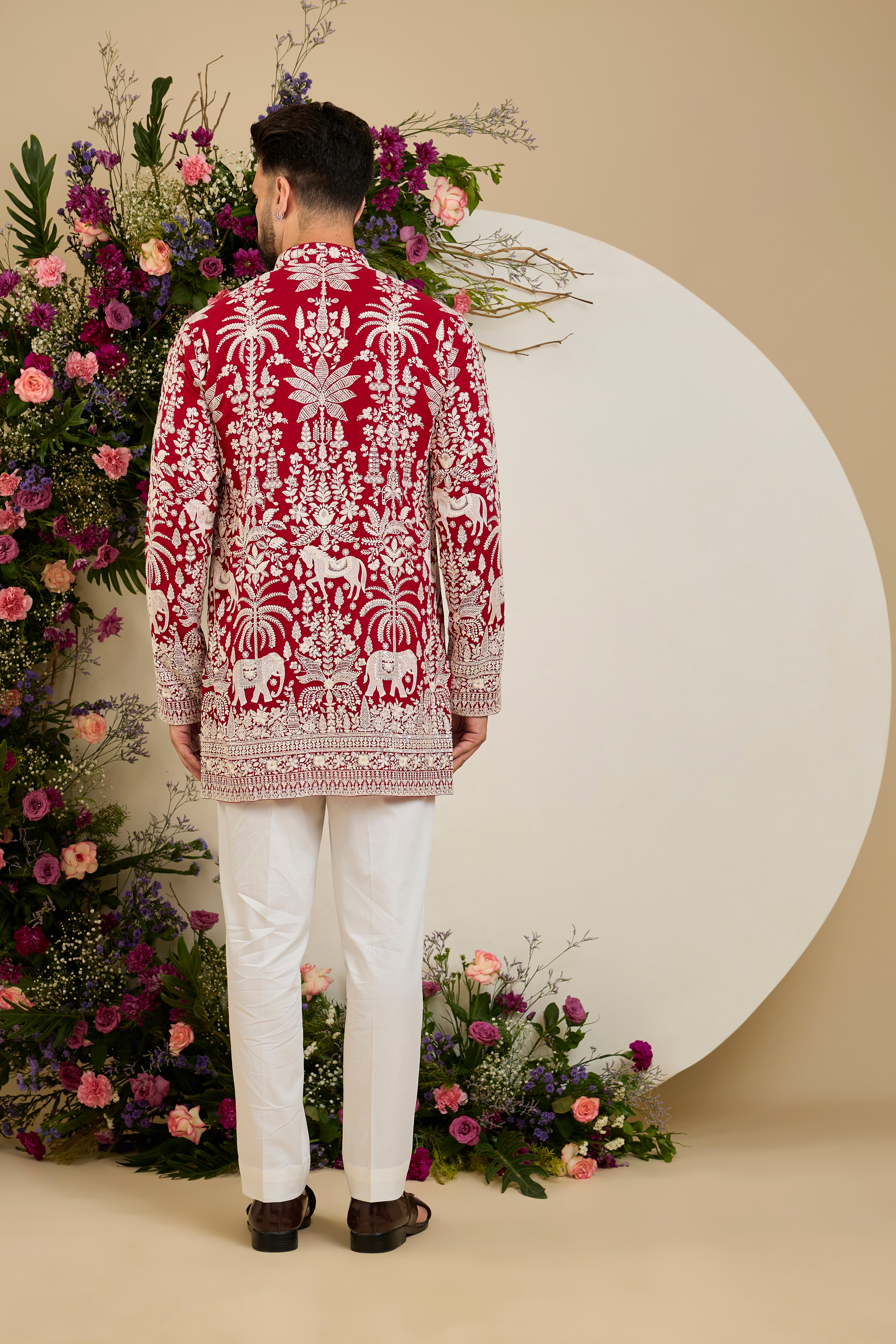 Red short kurta with tropical flora and fauna embroidery, ivory threadwork, and delicate sequin detailing for refined occasion wear.