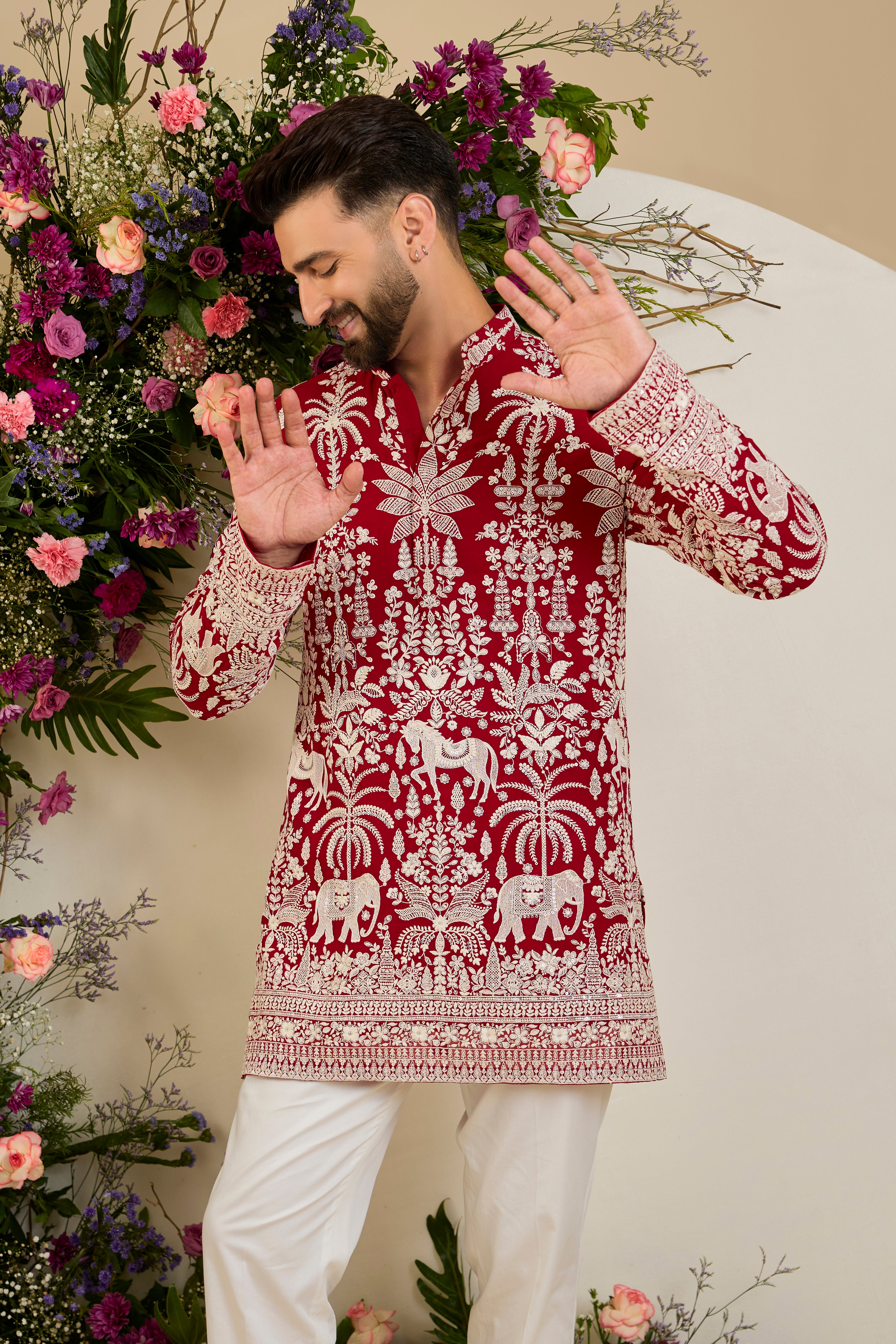 Red short kurta with tropical flora and fauna embroidery, ivory threadwork, and delicate sequin detailing for refined occasion wear.