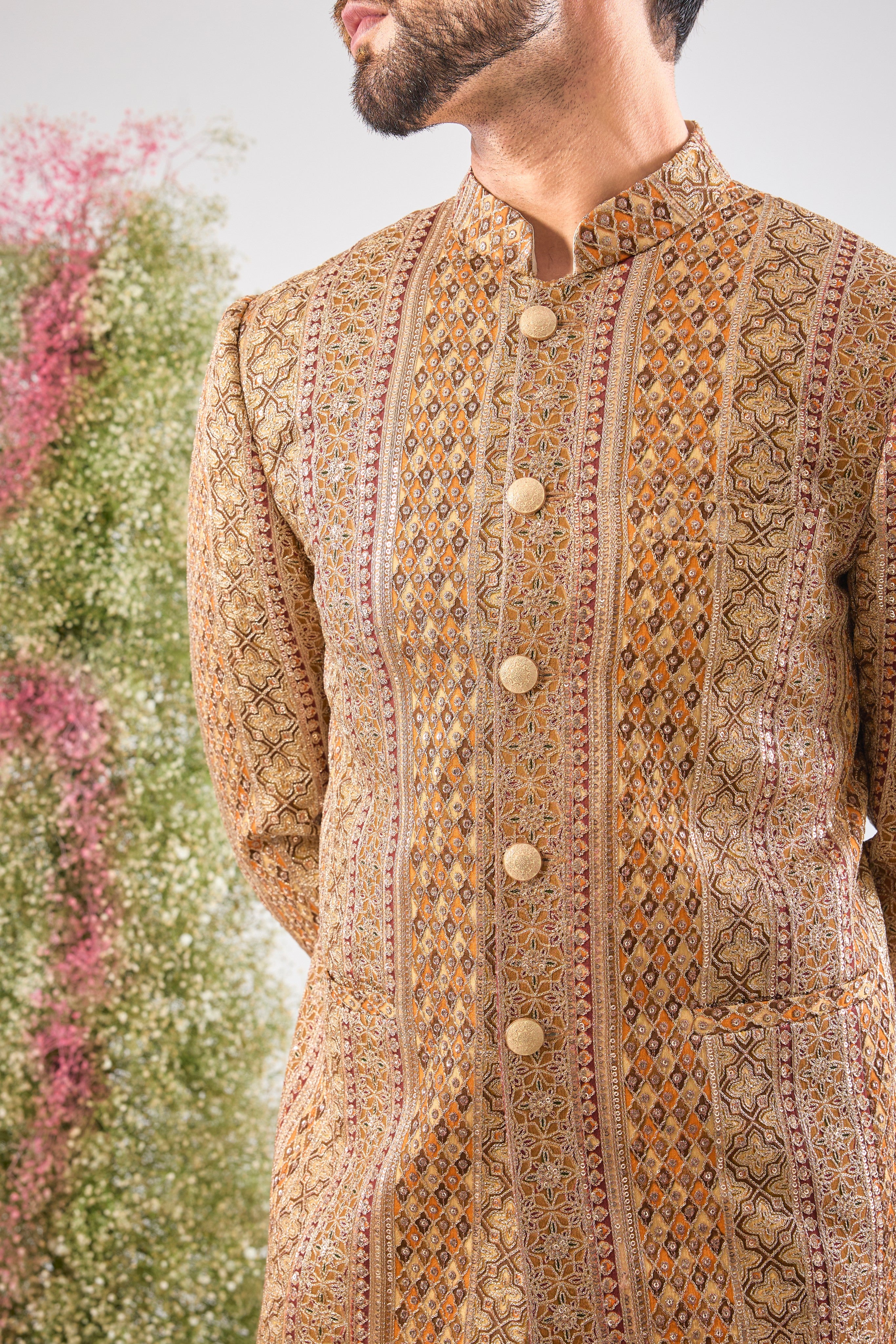 Artistry in vivid hues. This Mustard Bandhgala showcases opulent Heavy Zari Work and sequin accents, brilliantly integrating Shades of Green and Orange into the design.