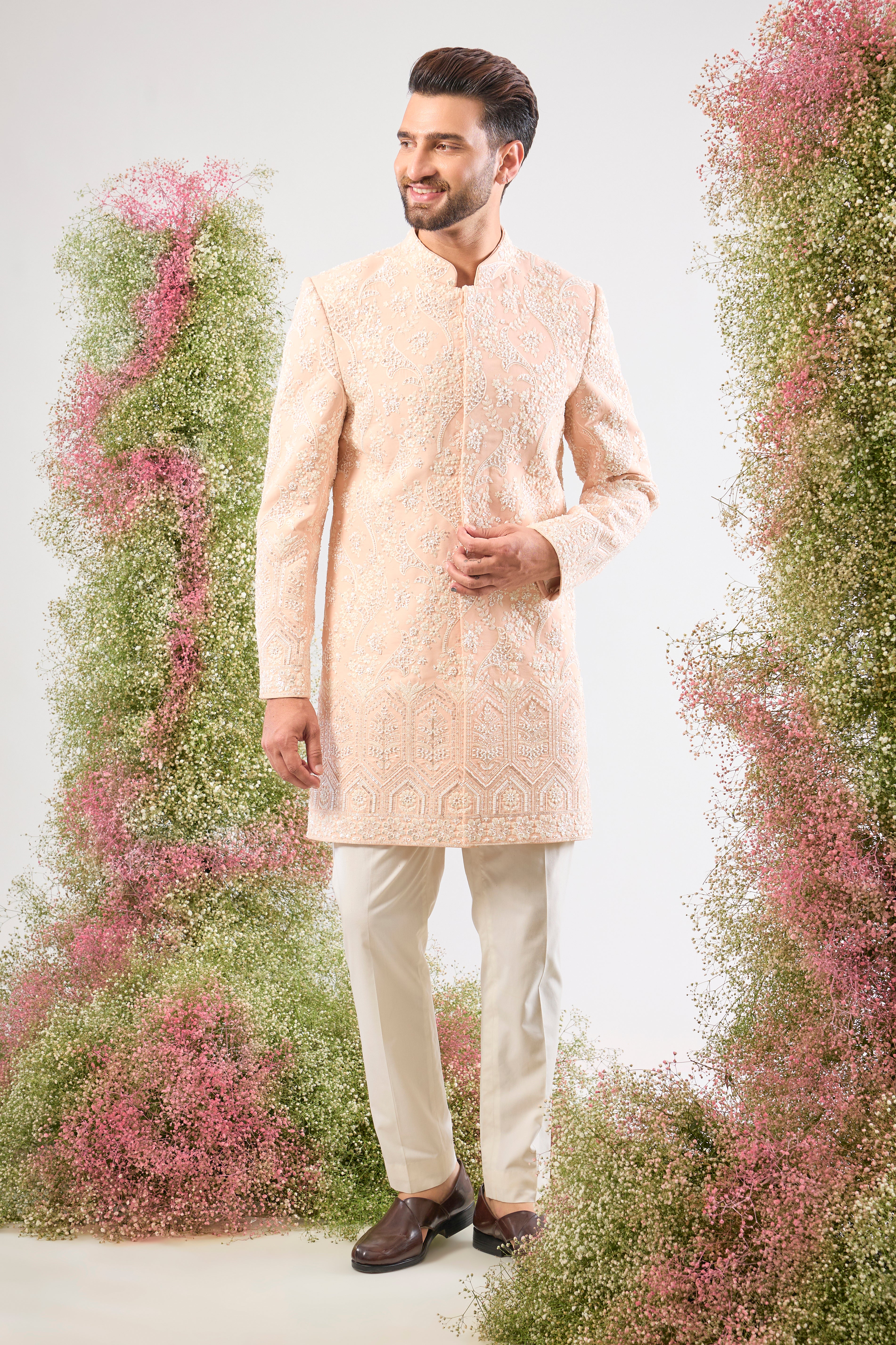 Artistry in attire! Our Pink Short Sherwani is adorned with a charming Floral Pattern brought to life using precise Hand Embroidered Cut Dana and shimmering, Delicate Sequins. The result is a sherwani that is both vibrant and exquisitely detailed. 🎨