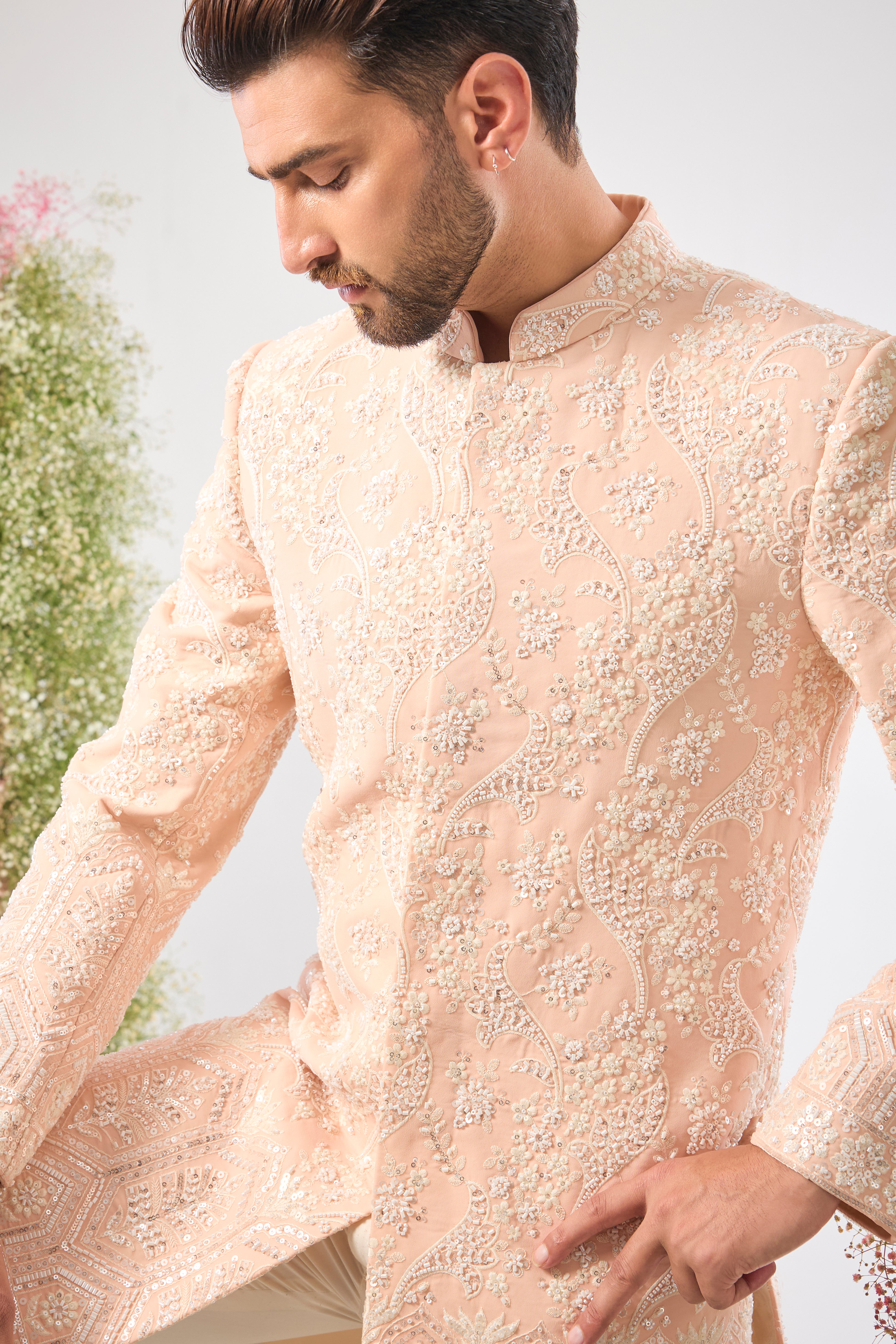 Artistry in attire! Our Pink Short Sherwani is adorned with a charming Floral Pattern brought to life using precise Hand Embroidered Cut Dana and shimmering, Delicate Sequins. The result is a sherwani that is both vibrant and exquisitely detailed. 🎨