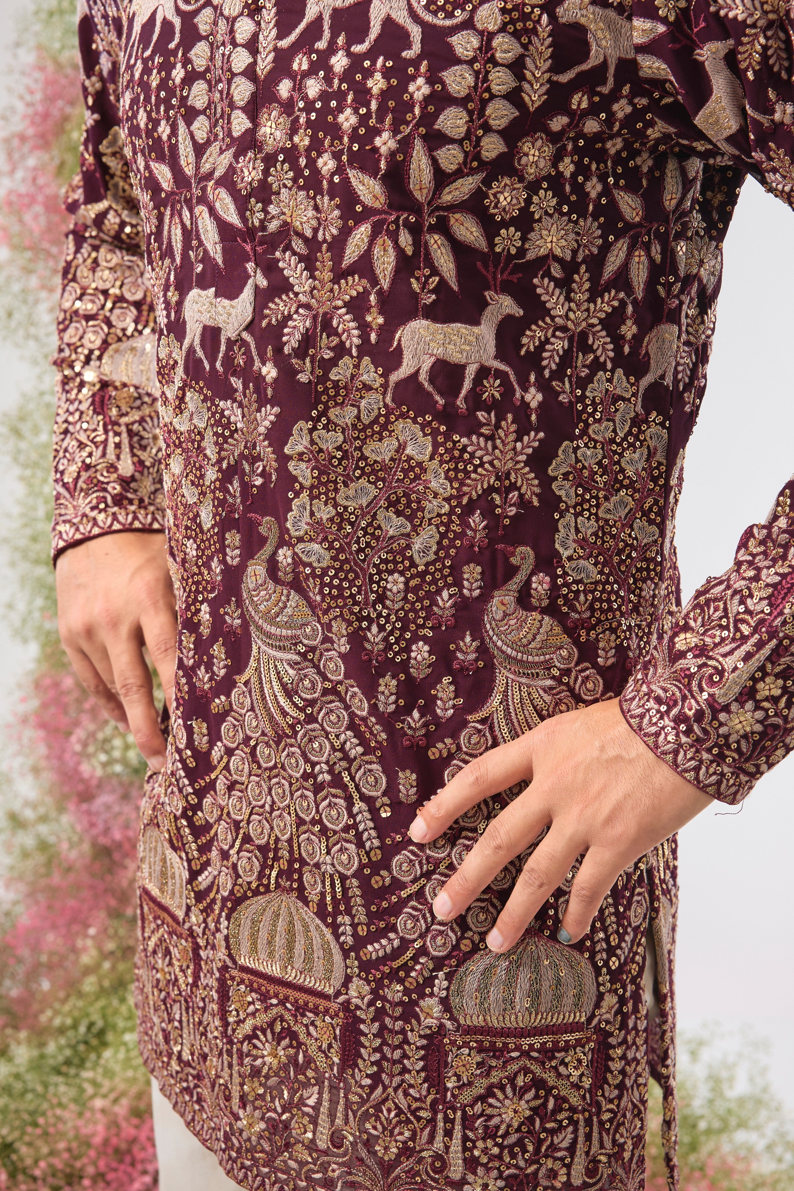 This Wine Short Kurta showcases stunning artistry, where Detailed Royal Darbars meet lush Flora and Fauna Figures. The entire design is beautifully textured and illuminated by rich Zari and Sequins.