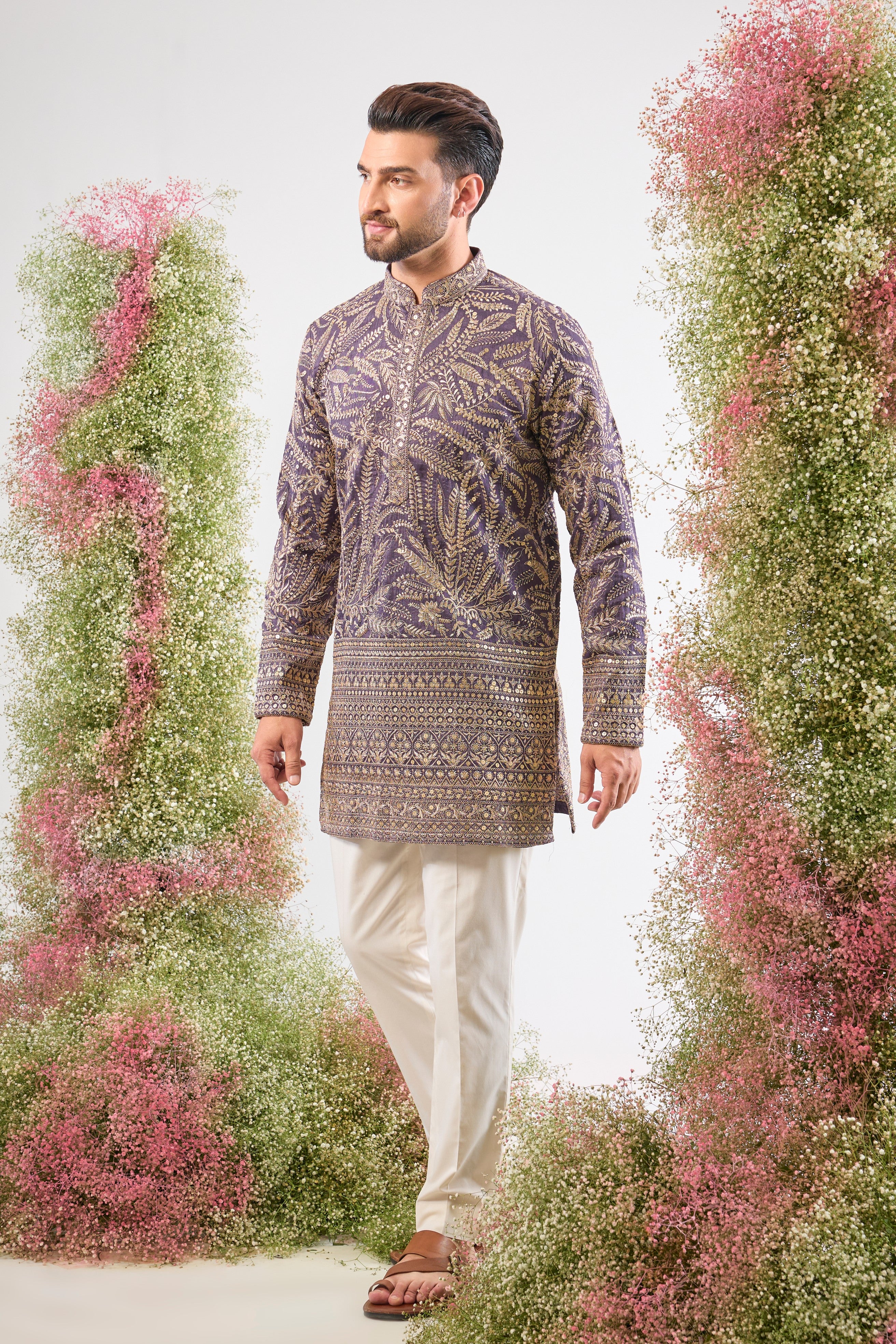 his Purple Mauve Short Zari Kurta is adorned with exquisite Detailed Floral Embroidery and shimmering sequins, creating incredible texture. The classic heavy ghera adds a majestic flow to the short silhouette.