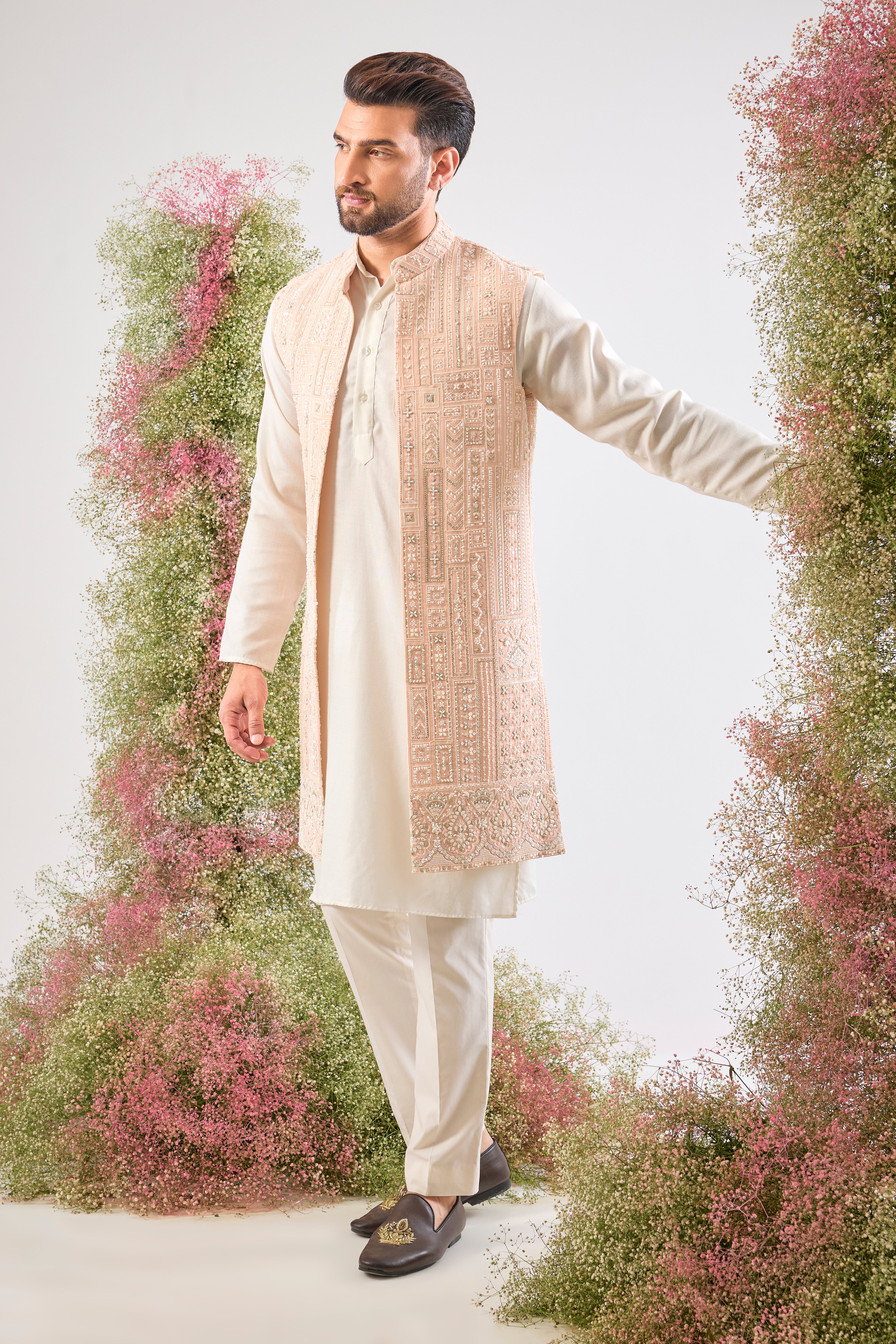 Our Long Open Jacket features exquisite Hind Hand Work, meticulously crafted with shimmering White Cut Dana and Sequin detailing arranged in a sharp Geometrical Pattern. This jacket is the perfect blend of artisanal skill and contemporary design.