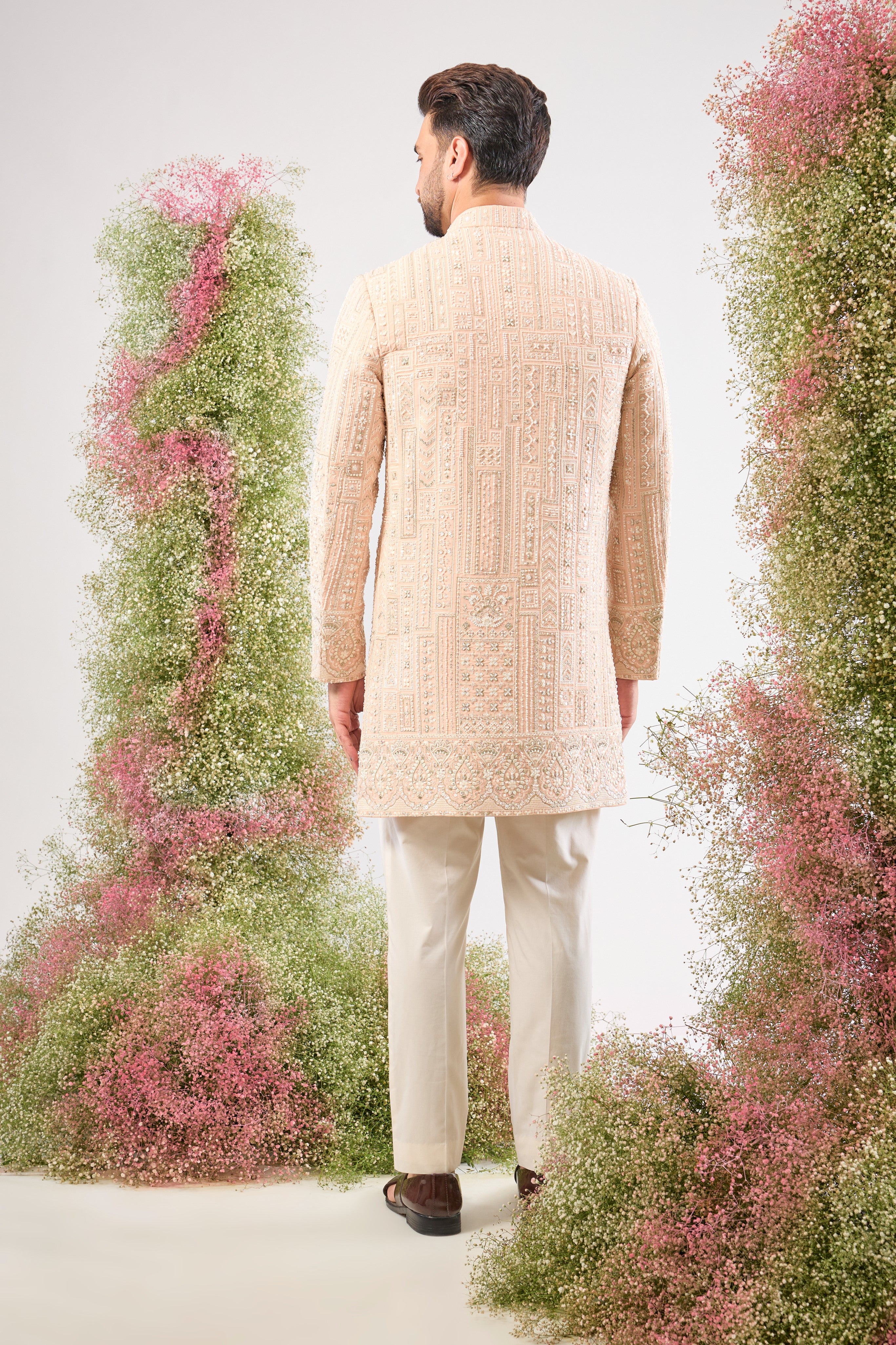 Our Pink Short Sherwani features a striking Geometrically Embroidered pattern, meticulously brought to life with exquisite Hand Work White Cut Dana and Sequin detailing.