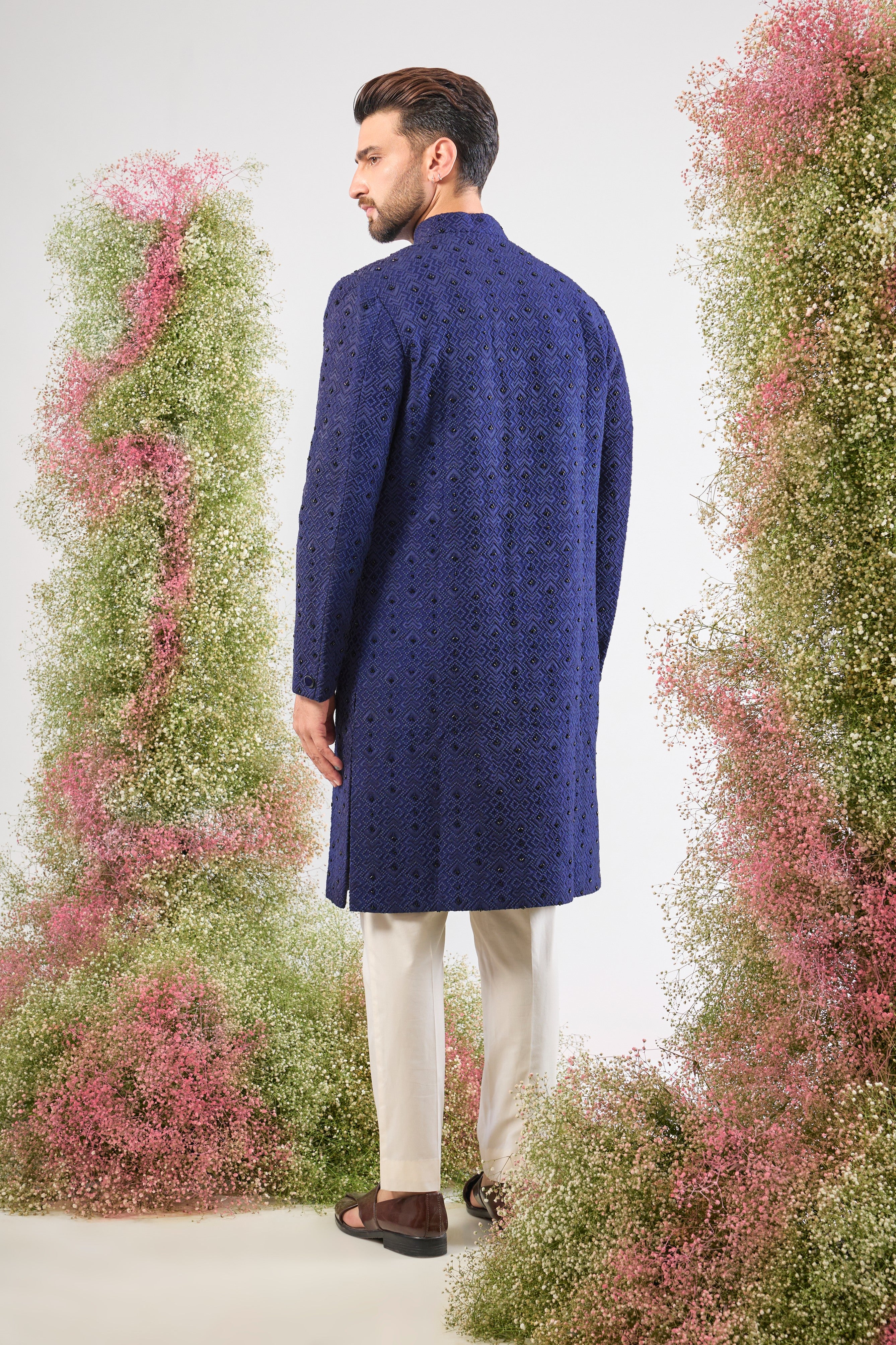 This Sherwani showcases a contemporary Geometrically Embroidered pattern, beautifully contrasted with the subtle, dark sparkle of Hand Embroidered Black Cut Dana.