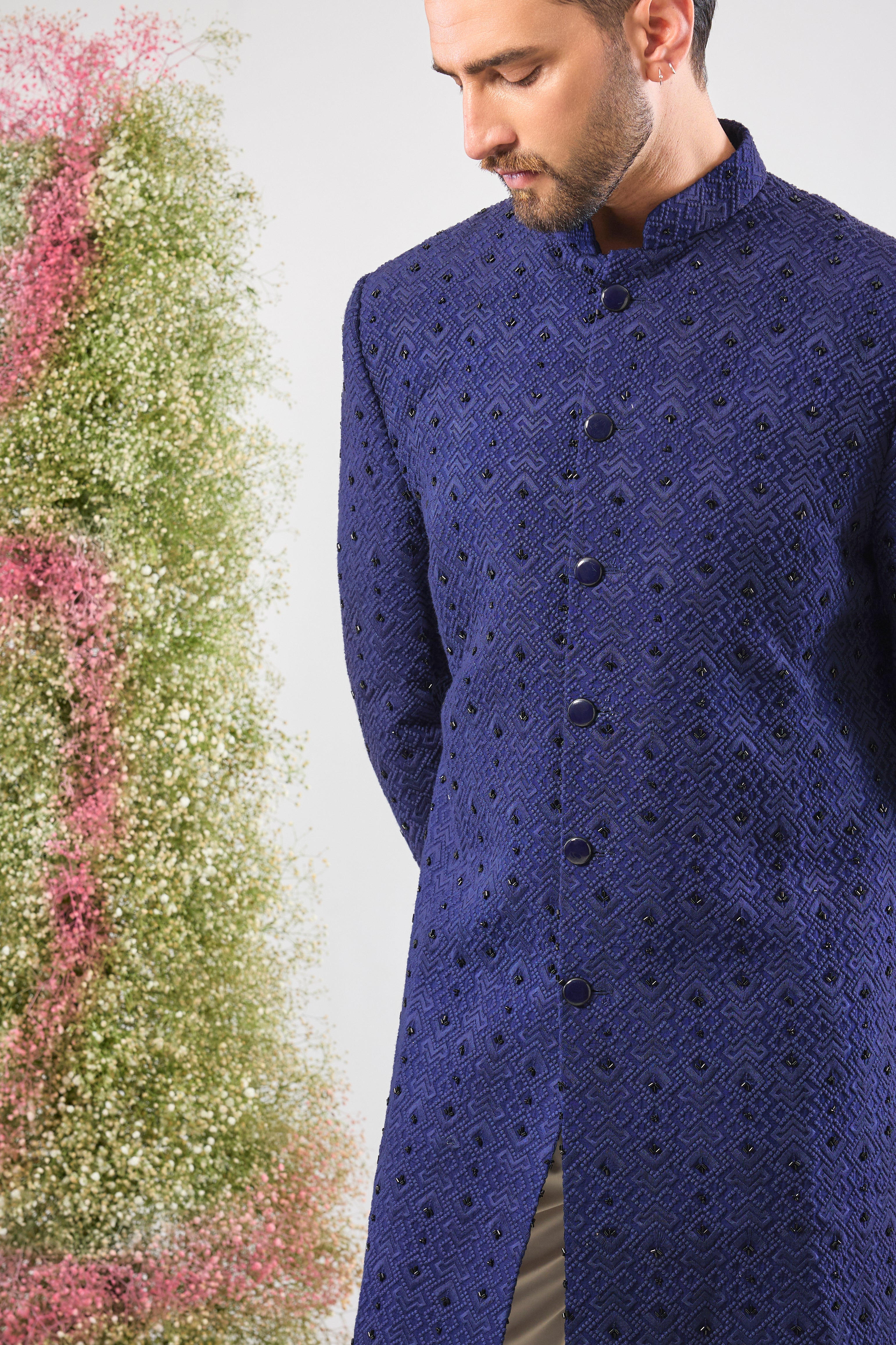This Sherwani showcases a contemporary Geometrically Embroidered pattern, beautifully contrasted with the subtle, dark sparkle of Hand Embroidered Black Cut Dana.