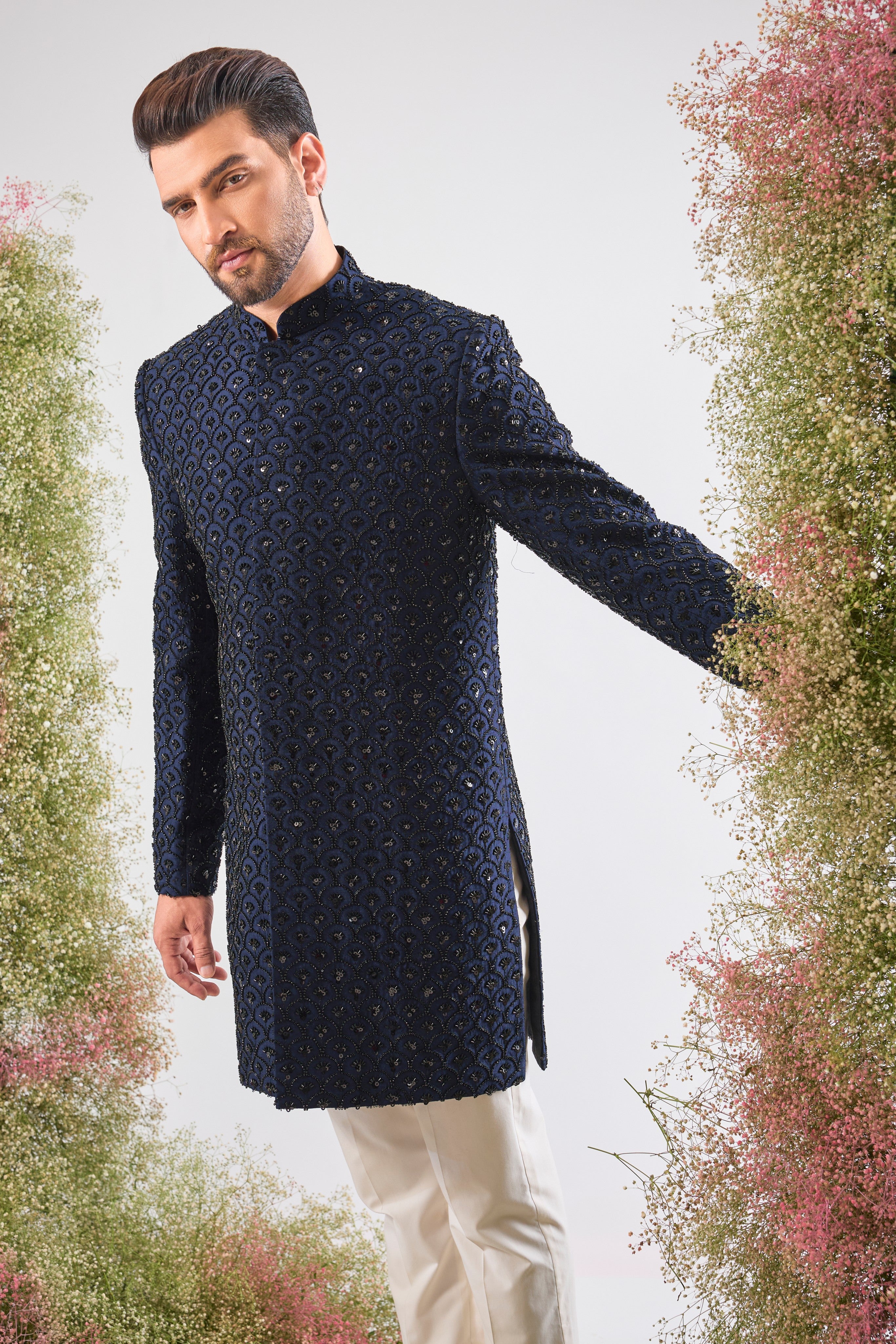 This Short Sherwani showcases a rich, traditional pattern, beautifully contrasted with the subtle, dark sparkle of Hand Embroidered Black Cut Dana.