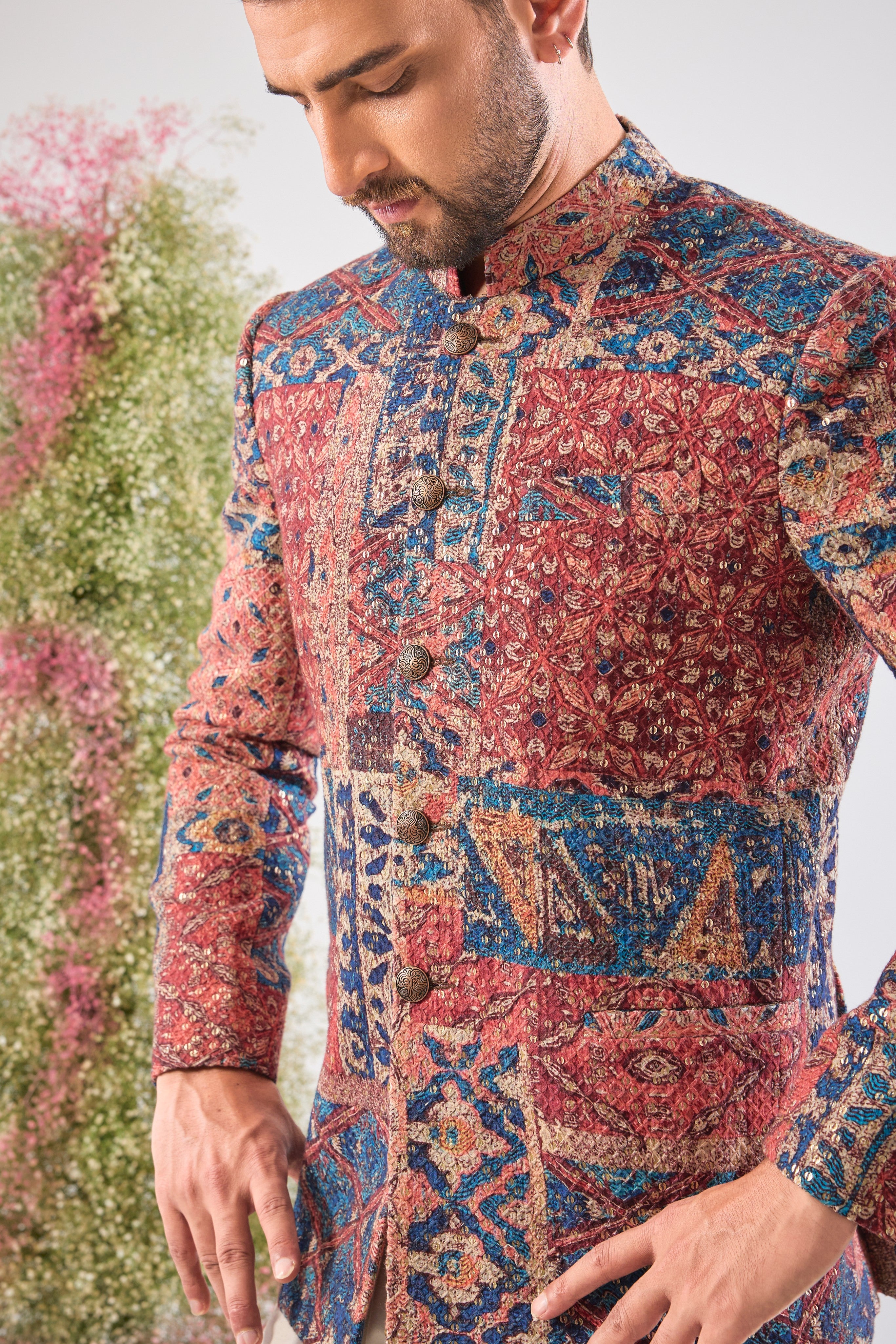 his Multi-coloured Bandhgala showcases a mesmerizing Abstract Royal Geometrical Print that is beautifully layered with fine Thread Work. The inclusion of Sequin Detailing ensures a subtle, festive shimmer, creating a truly dynamic and luxurious garment.