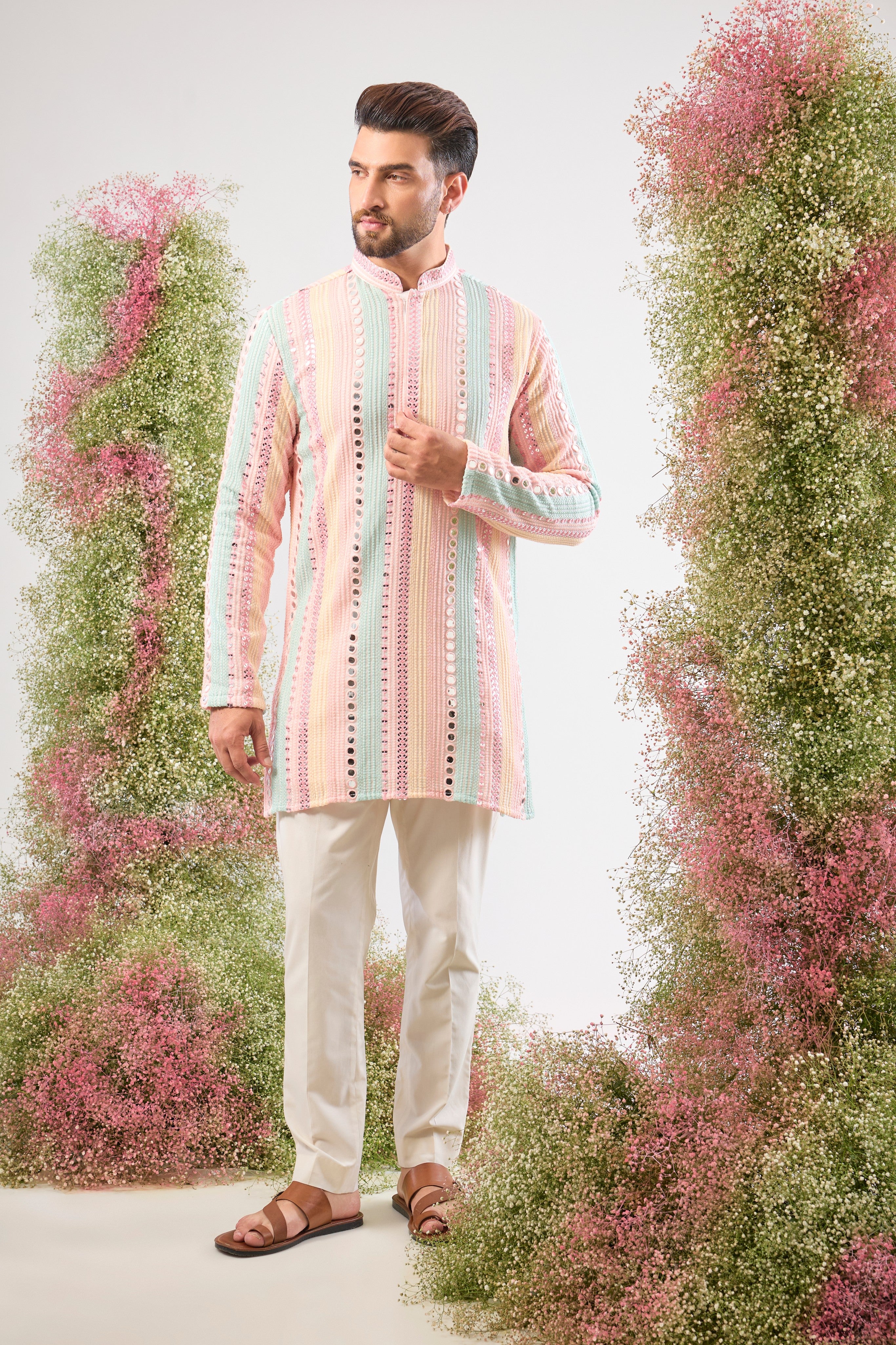 This Short Mirror Work Kurta showcases structured Pintucks Style Stripes filled with rich Multi-coloured Thread work, subtly enhanced by Delicate Sequin Work. The combination is utterly magical, offering a sophisticated yet joyful aesthetic.